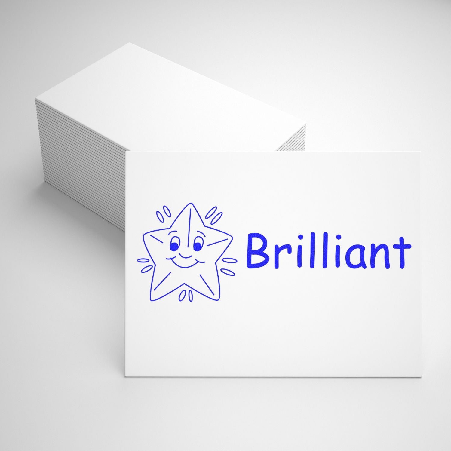 A stack of white cards with a blue star and the word Brilliant stamped on the top card using the Large Pre-Inked Brilliant Stamp.