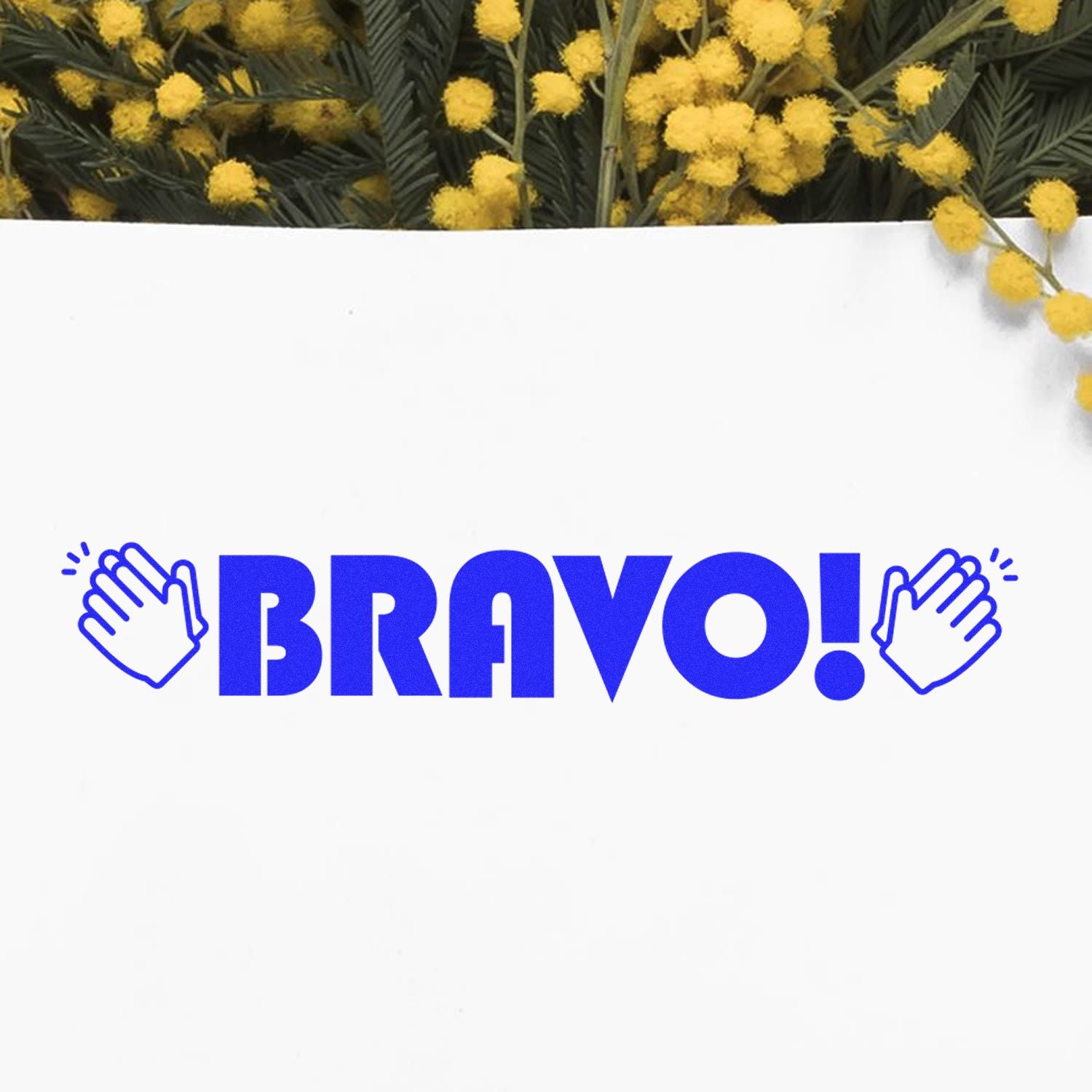 Large Pre-Inked Bravo with Hands Stamp in blue ink on white paper, surrounded by yellow flowers in the background.