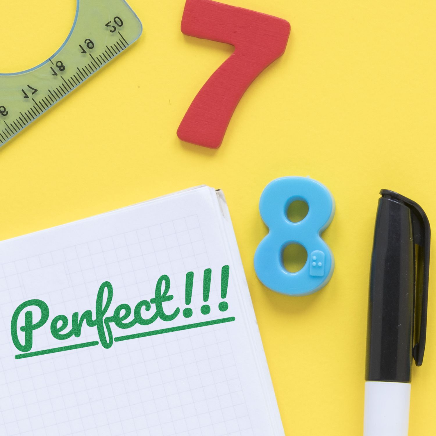 Large Pre-Inked Perfect Stamp on a notebook with Perfect!!! written, surrounded by a pen, ruler, and colorful numbers on a yellow background.