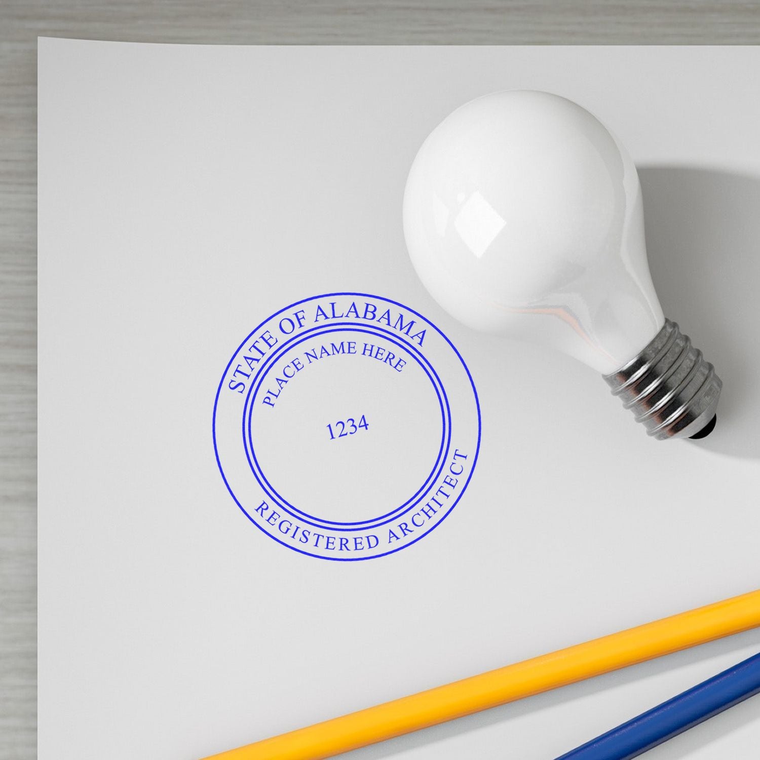 Digital Alabama Architect Stamp, Electronic Seal for Alabama Architect, imprinted on paper with a light bulb and pencils nearby.