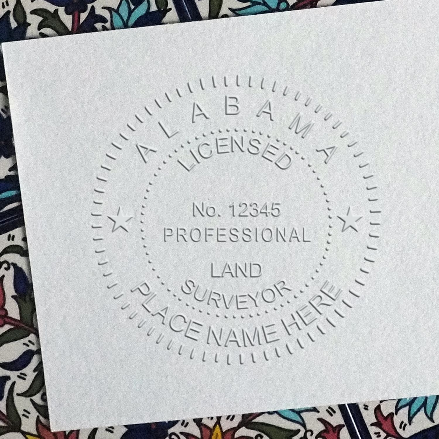 A lifestyle photo showing a stamped image of the Handheld Alabama Land Surveyor Seal on a piece of paper