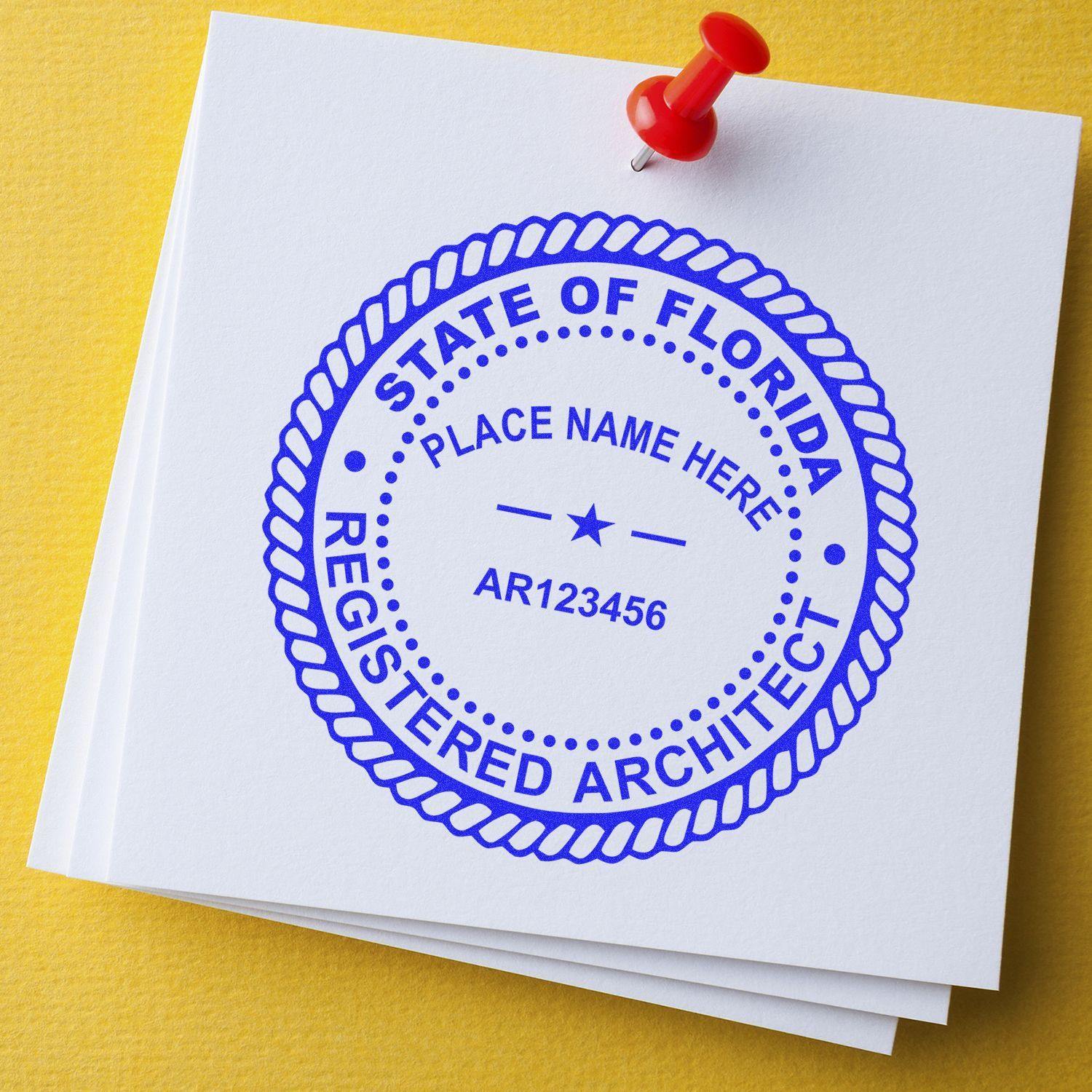 A stack of white papers with a blue STATE OF FLORIDA REGISTERED ARCHITECT seal stamped on top, created using the Architect eSeal Electronic Image Stamp of Seal, pinned with a red pushpin on a yellow surface.