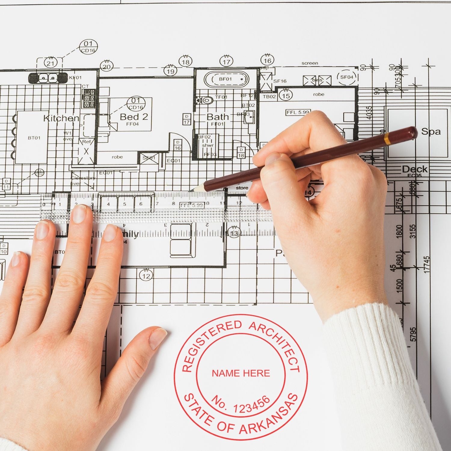 Person using Self Inking Arkansas Architect Stamp on architectural blueprint with a pen in hand.