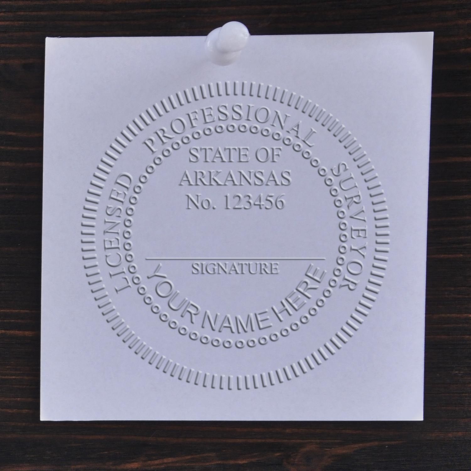 An in use photo of the Hybrid Arkansas Land Surveyor Seal showing a sample imprint on a cardstock