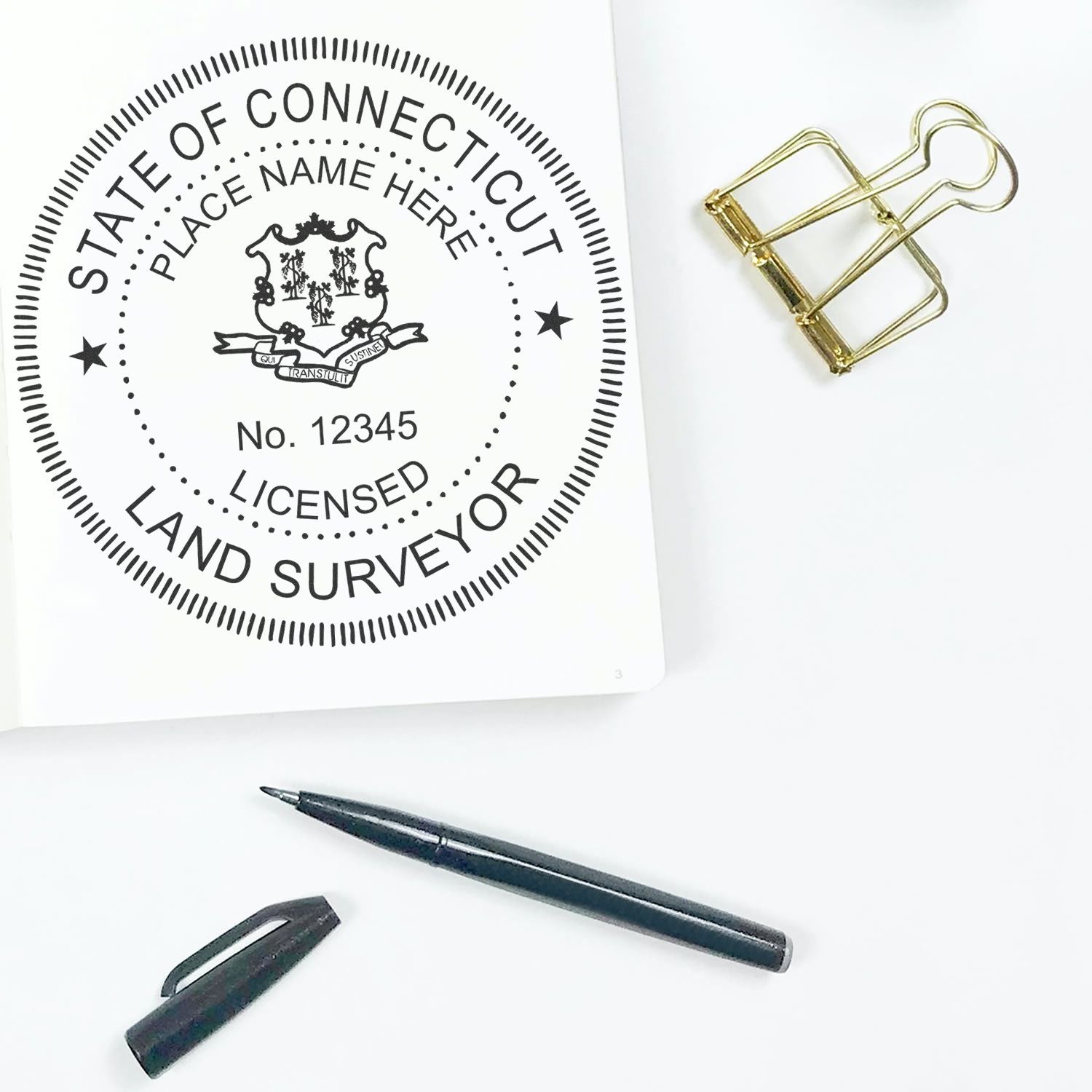 Premium MaxLight Pre-Inked Connecticut Surveyors Stamp on paper with pen, cap, and gold binder clip on white background.