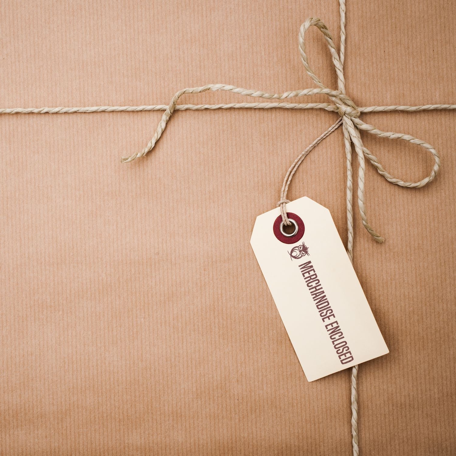 A brown paper package tied with string and a tag stamped with MERCHANDISE ENCLOSED using the Custom Self Inking Stamp Trodat 4915 Size 1 x 2-3/4.