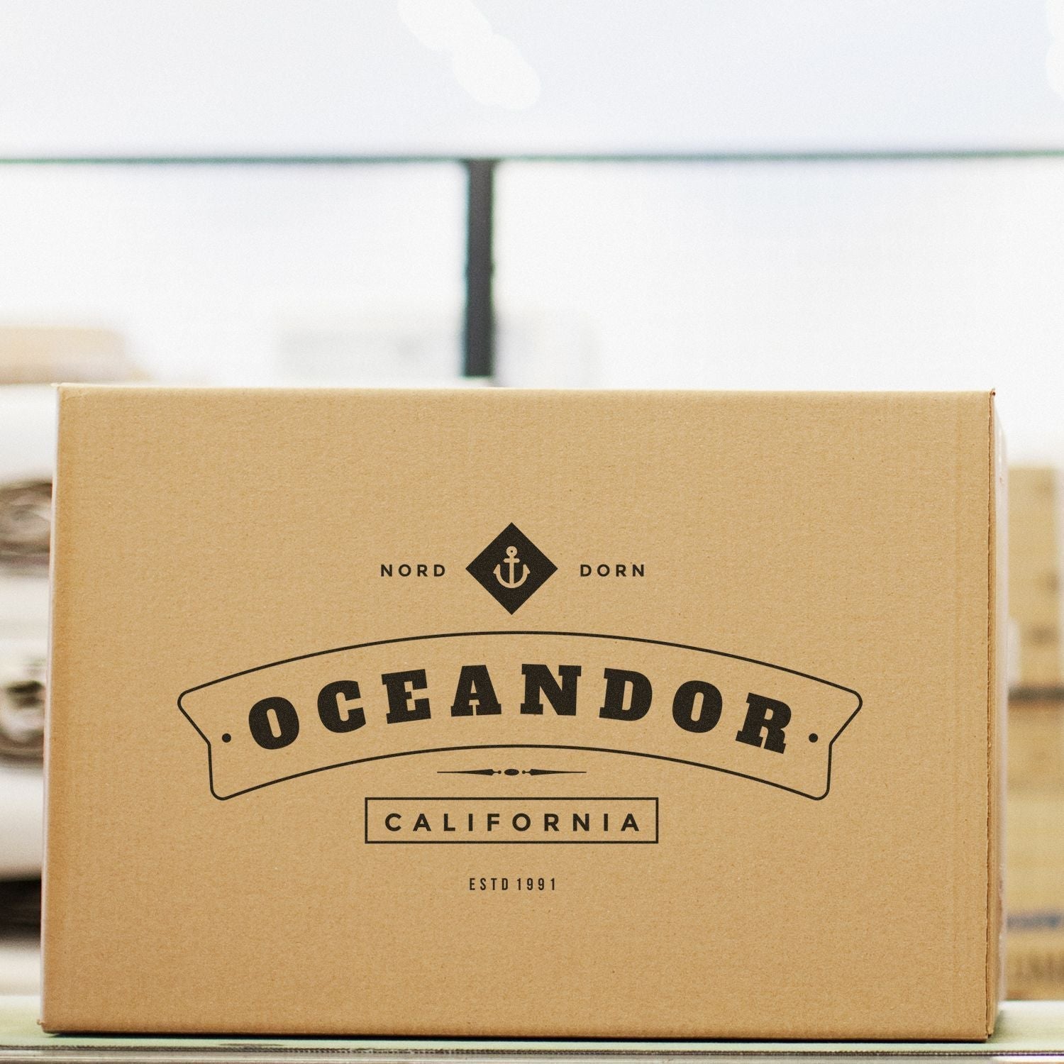 A cardboard box stamped with Oceandor California using a Custom Rubber Stamp Size 5 x 6, placed on a table in a warehouse setting.