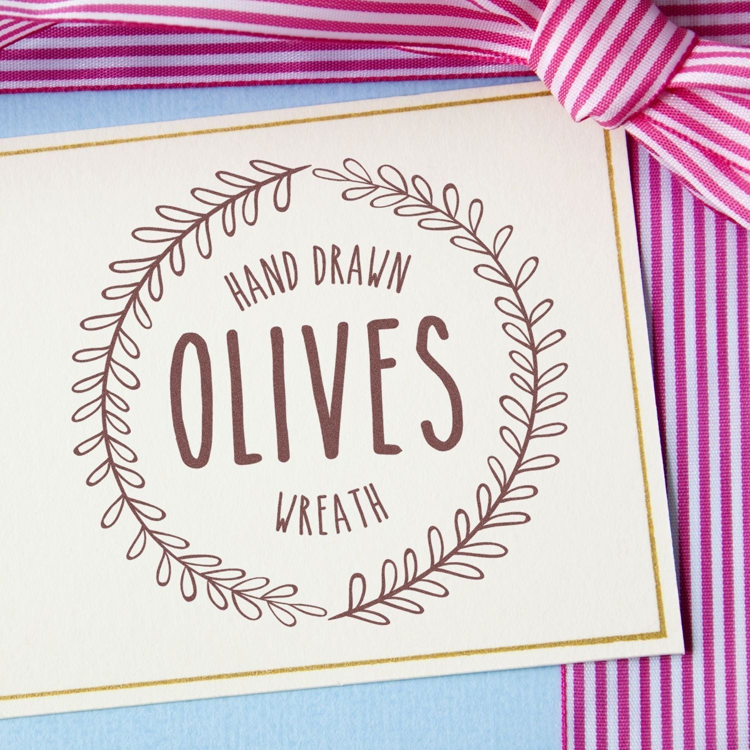 A card stamped with Hand Drawn Olives Wreath using Custom Self-Inking Stamp Trodat 52045 (Size: 1-3/4 Diameter) on a striped pink ribbon background.