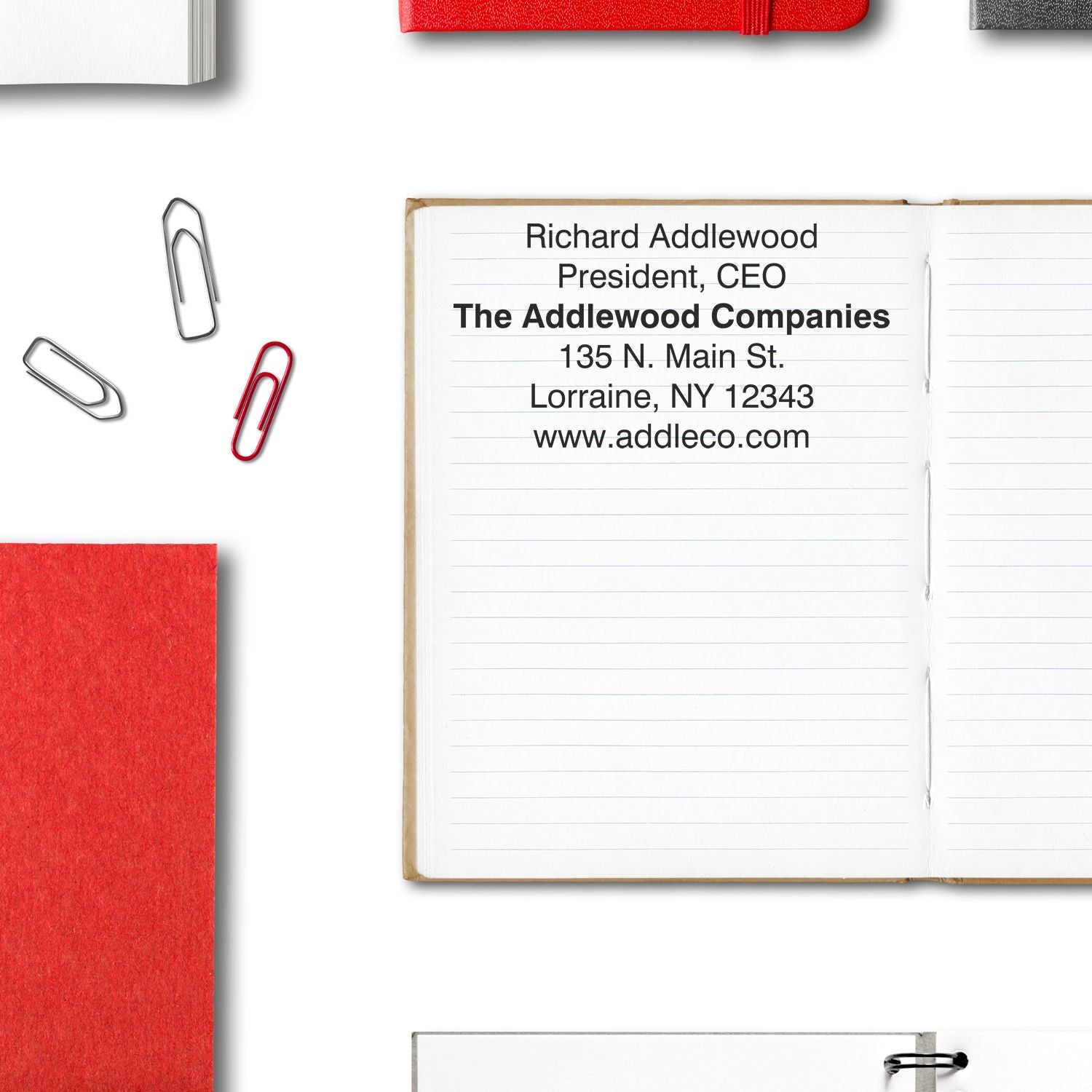 6 Line Custom Rubber Stamp with Wood Handle used to stamp contact details on an open notebook, surrounded by office supplies.