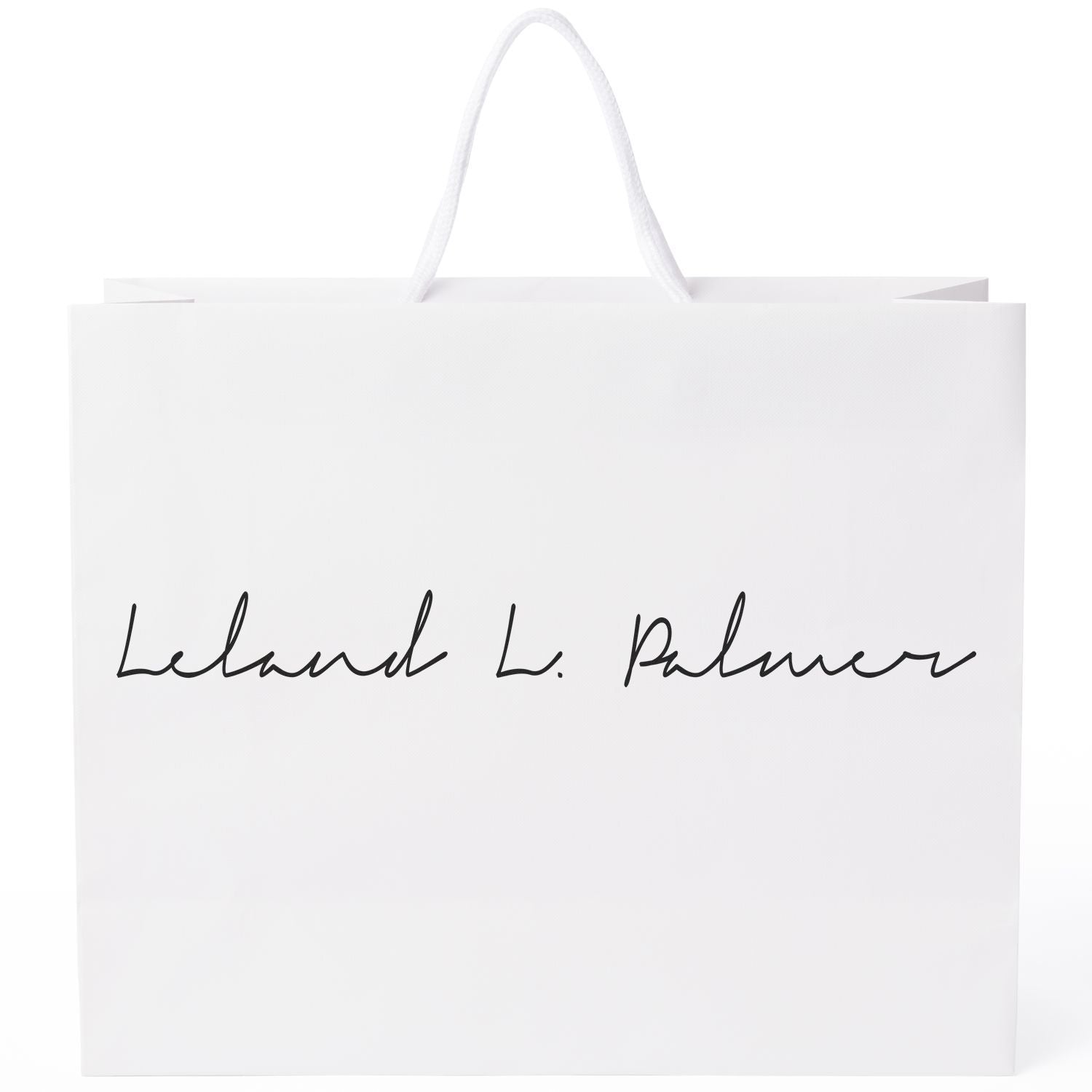 White shopping bag with Leland L. Palmer stamped using Custom Rubber Stamp Size 1 x 10 in black ink.