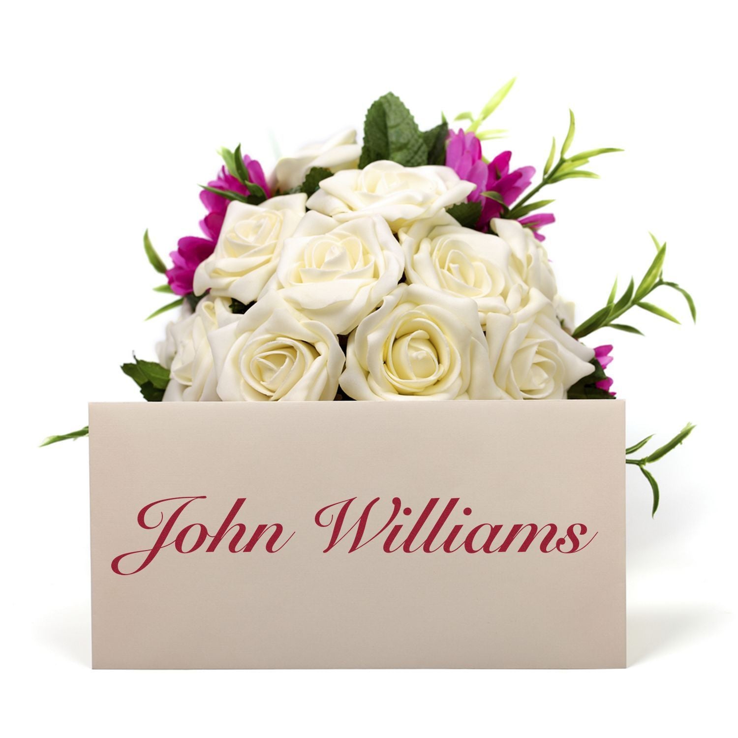 A Custom Rubber Stamp Size 2 x 9 is used to stamp John Williams in red ink on a white card placed in front of a bouquet of white roses.