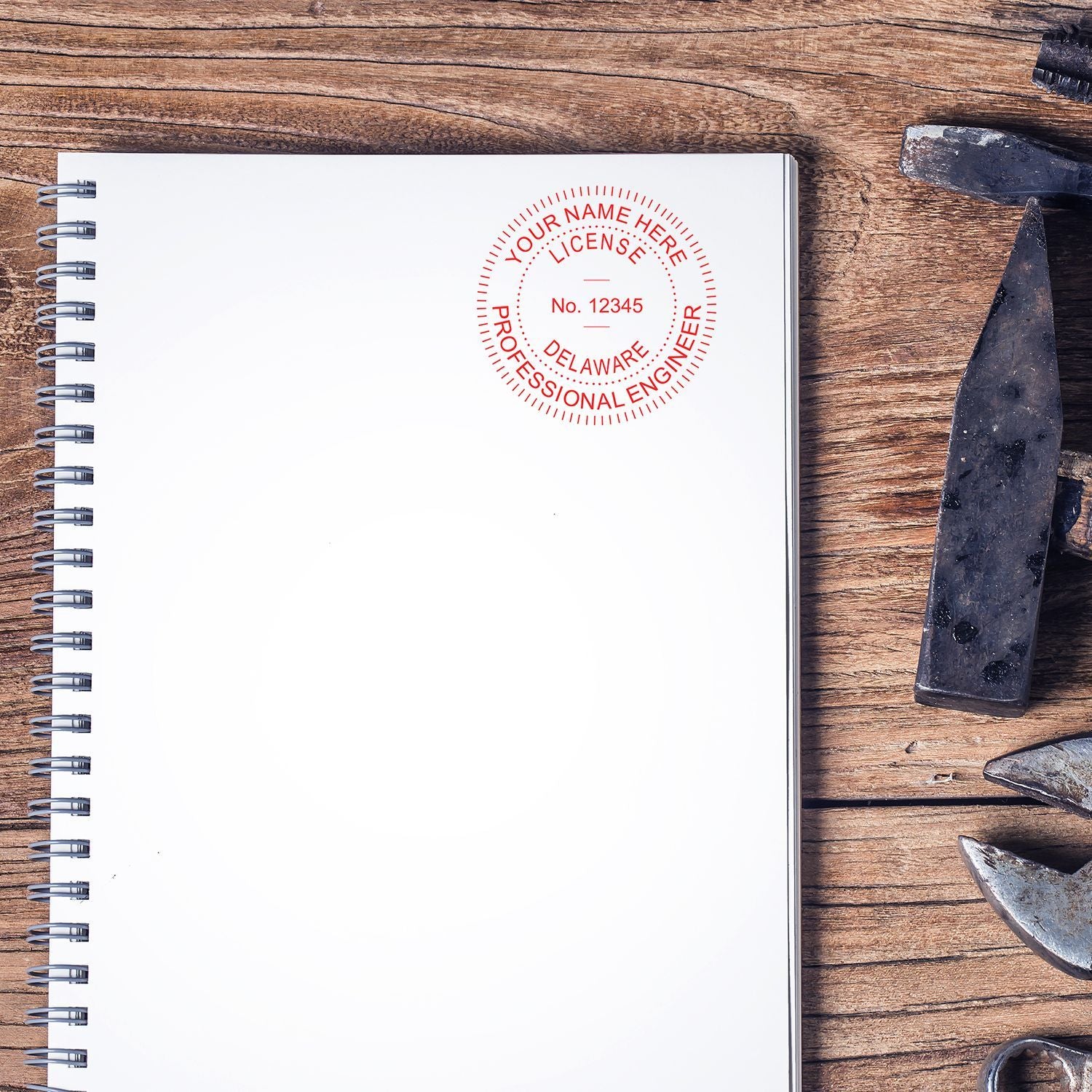 A notebook on a wooden table with a Professional Engineer eSeal Electronic Image Stamp of Seal imprinted on the top right corner. Various tools are placed to the right of the notebook.