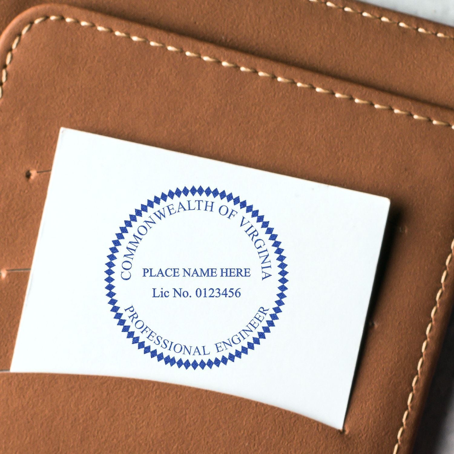 A close-up of a business card with a blue circular seal that reads COMMONWEALTH OF VIRGINIA, PROFESSIONAL ENGINEER using the Professional Engineer eSeal Electronic Image Stamp of Seal, placed on a brown leather wallet.