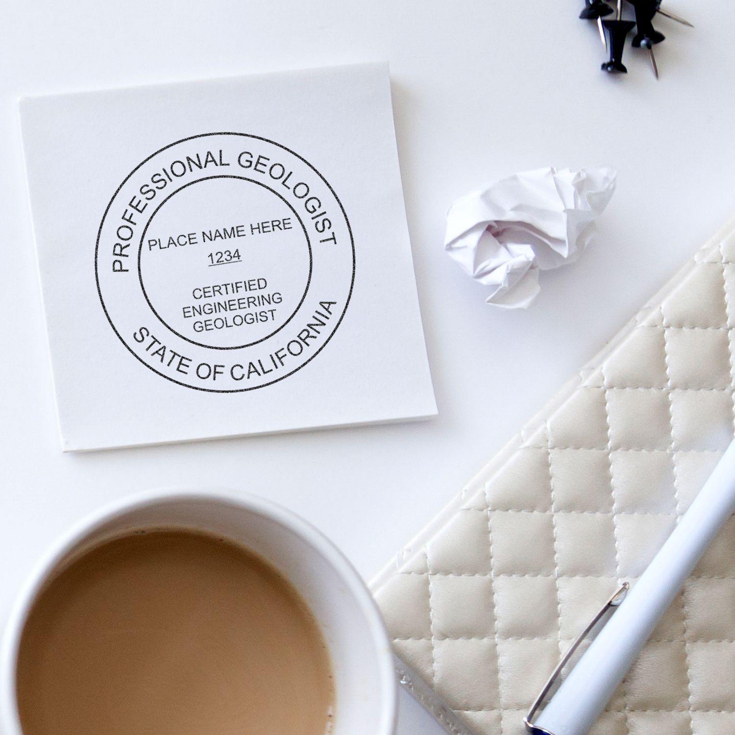 Engineering Geologist Regular Rubber Stamp of Seal on a white paper with text 'Professional Geologist, State of California'. Surrounding items include a coffee cup, pen, crumpled paper, and push pins.