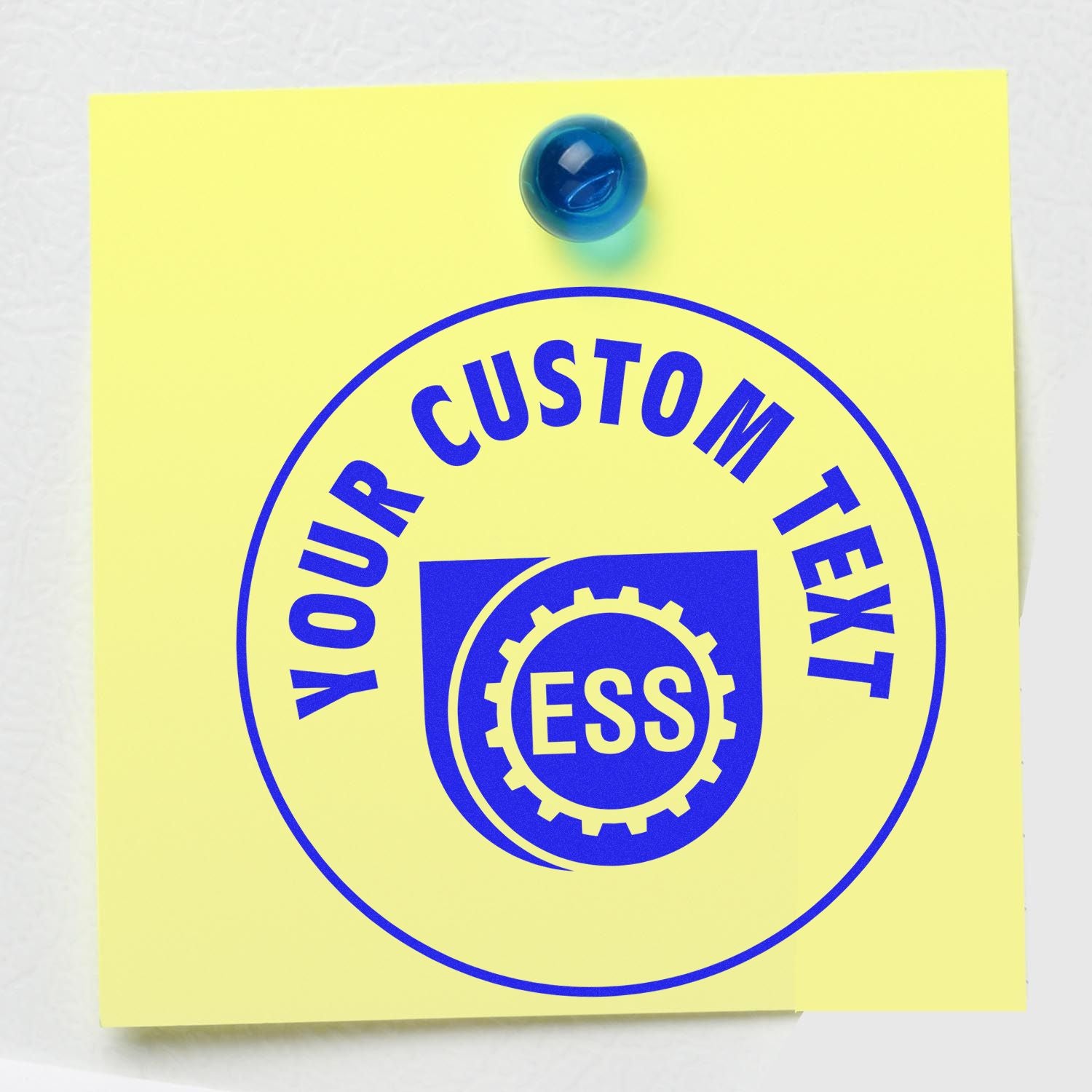 Yellow sticky note with a blue pin, stamped with YOUR CUSTOM TEXT and ESS using the Custom Rubber Stamp Size 3 Inch Diameter.