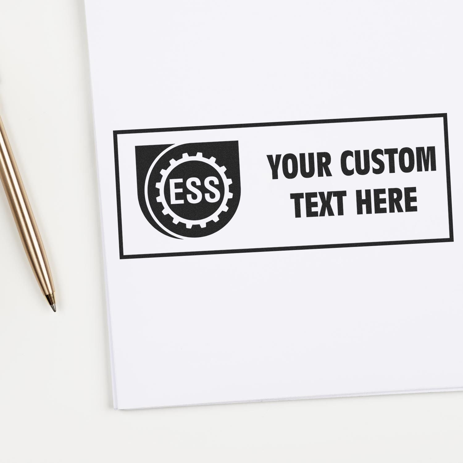 Custom Rubber Stamp Size 1 x 2 imprinting ESS YOUR CUSTOM TEXT HERE on white paper, with a gold pen beside it.