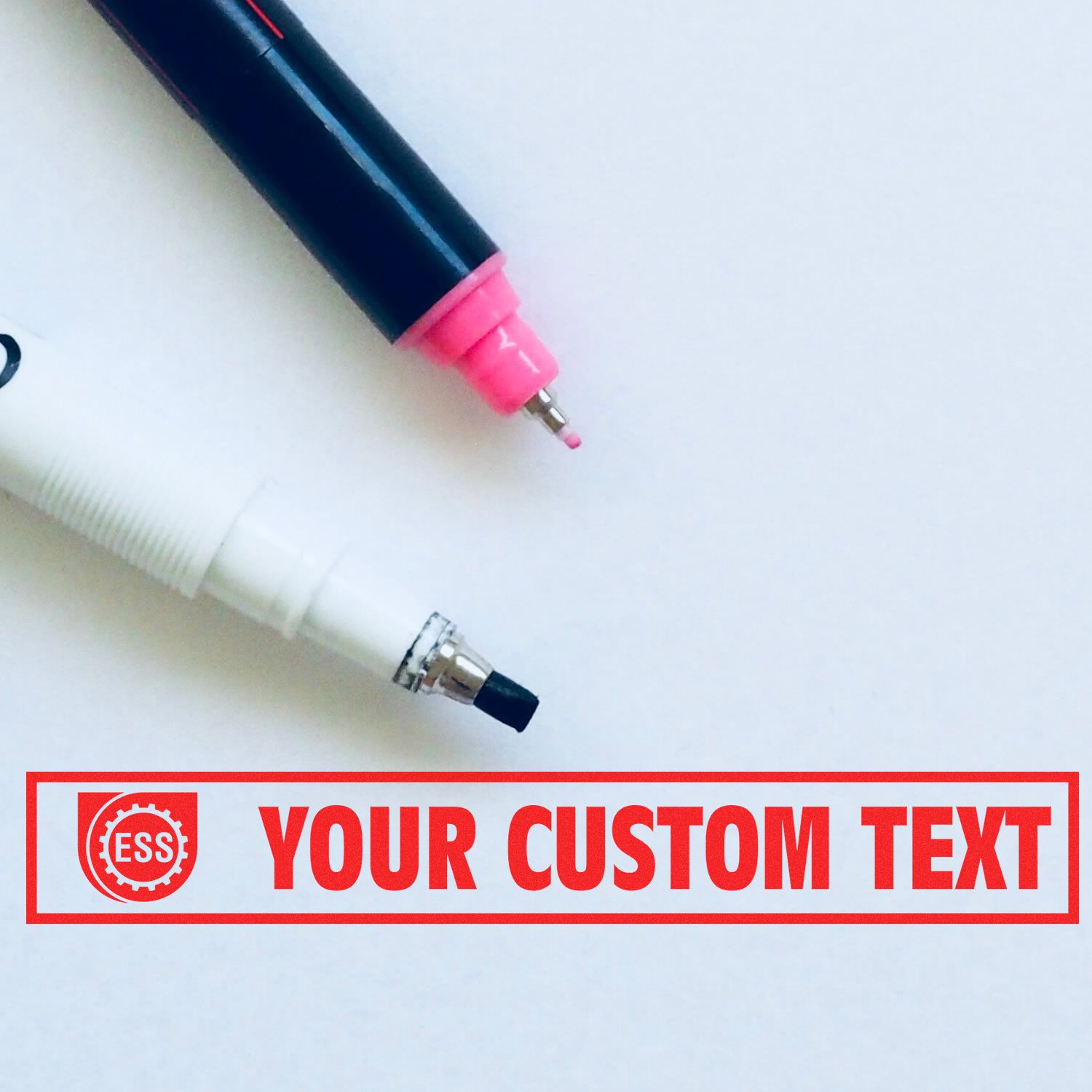 Two markers next to a Custom Rubber Stamp Size 2 x 7 with red text YOUR CUSTOM TEXT and an ESS logo on a white background.