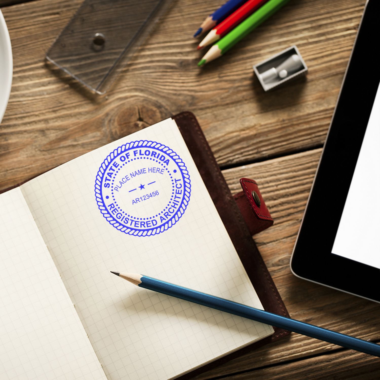 Self Inking Florida Architect Stamp used on a notebook, surrounded by a pencil, eraser, and tablet on a wooden desk.