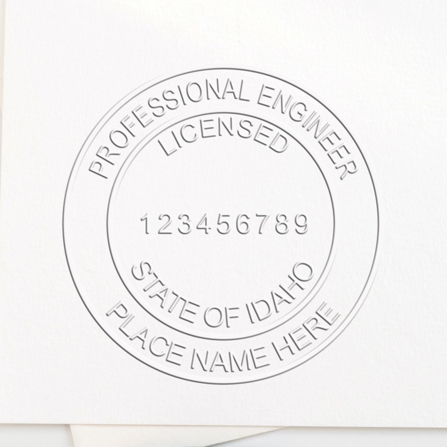 A lifestyle photo showing a stamped image of the Handheld Idaho Professional Engineer Embosser on a piece of paper