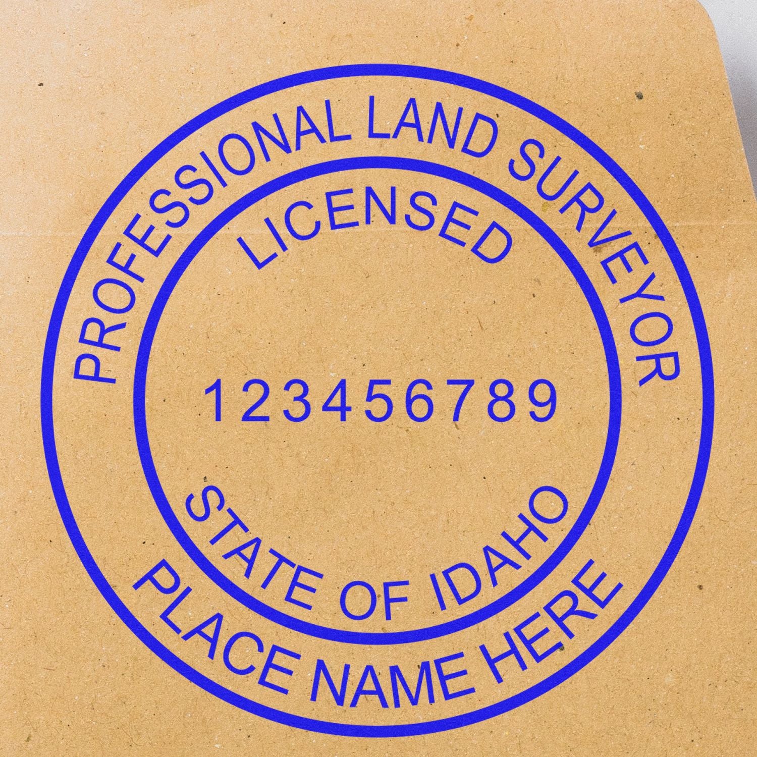 Self Inking Idaho Land Surveyor Stamp with blue ink on brown paper, displaying Professional Land Surveyor, Licensed, State of Idaho, Place Name Here.