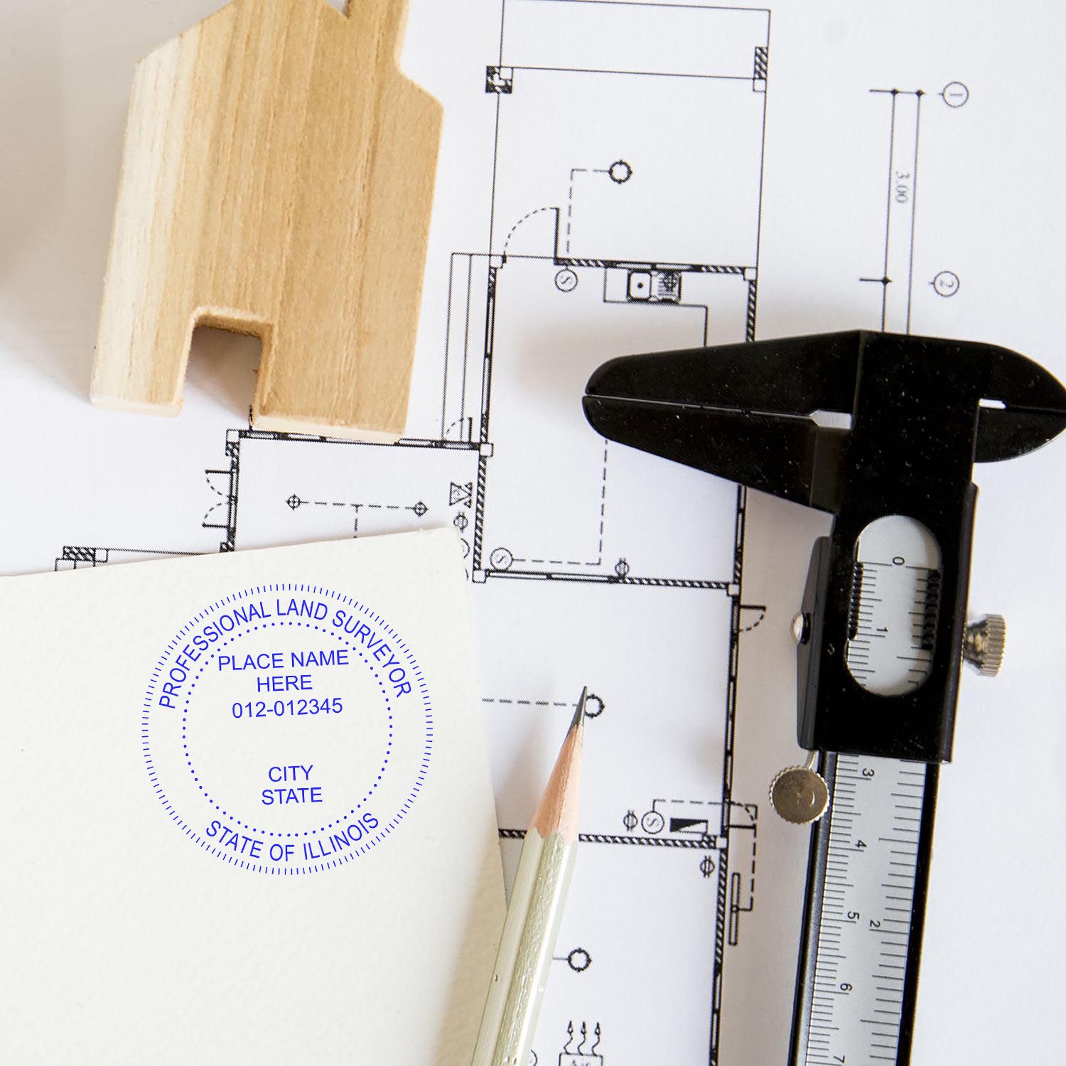 Self Inking Illinois Land Surveyor Stamp used on paper next to a pencil, caliper, and house model on architectural plans.