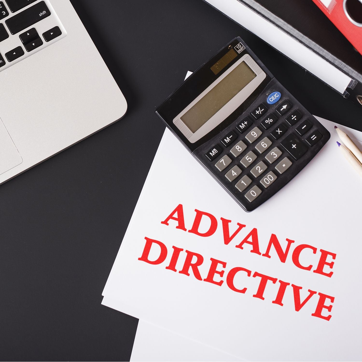 A Self Inking Advance Directive Stamp marks ADVANCE DIRECTIVE in red on documents, shown with a calculator and laptop on a black desk.