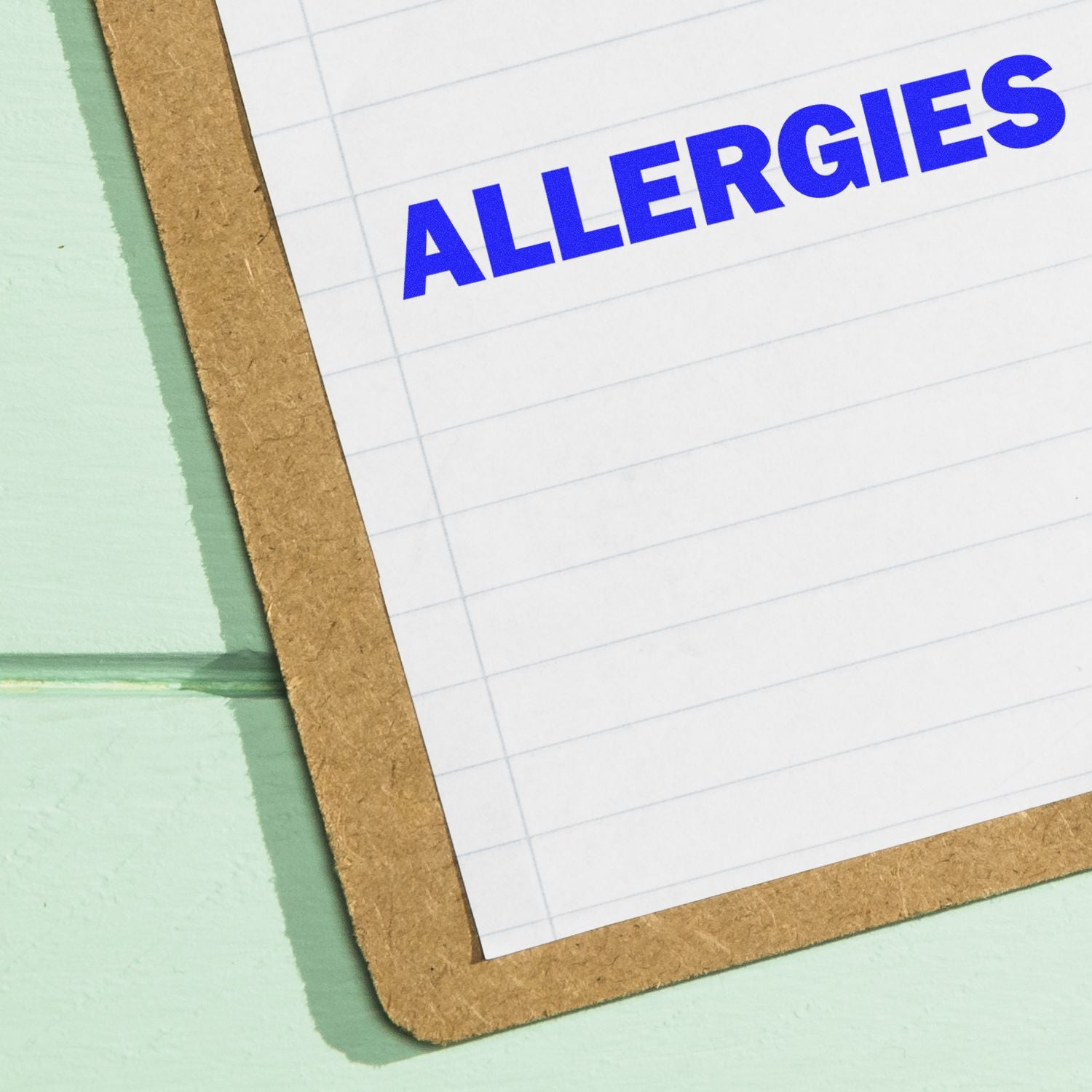 Large Allergies Rubber Stamp used on a lined paper attached to a clipboard, with the word ALLERGIES stamped in bold blue ink.