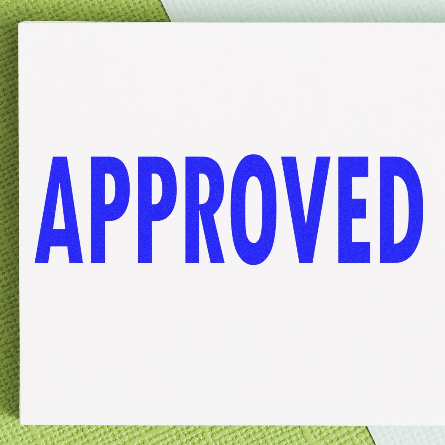 Approved rubber stamp in blue ink on a white card, placed on a green textured background.