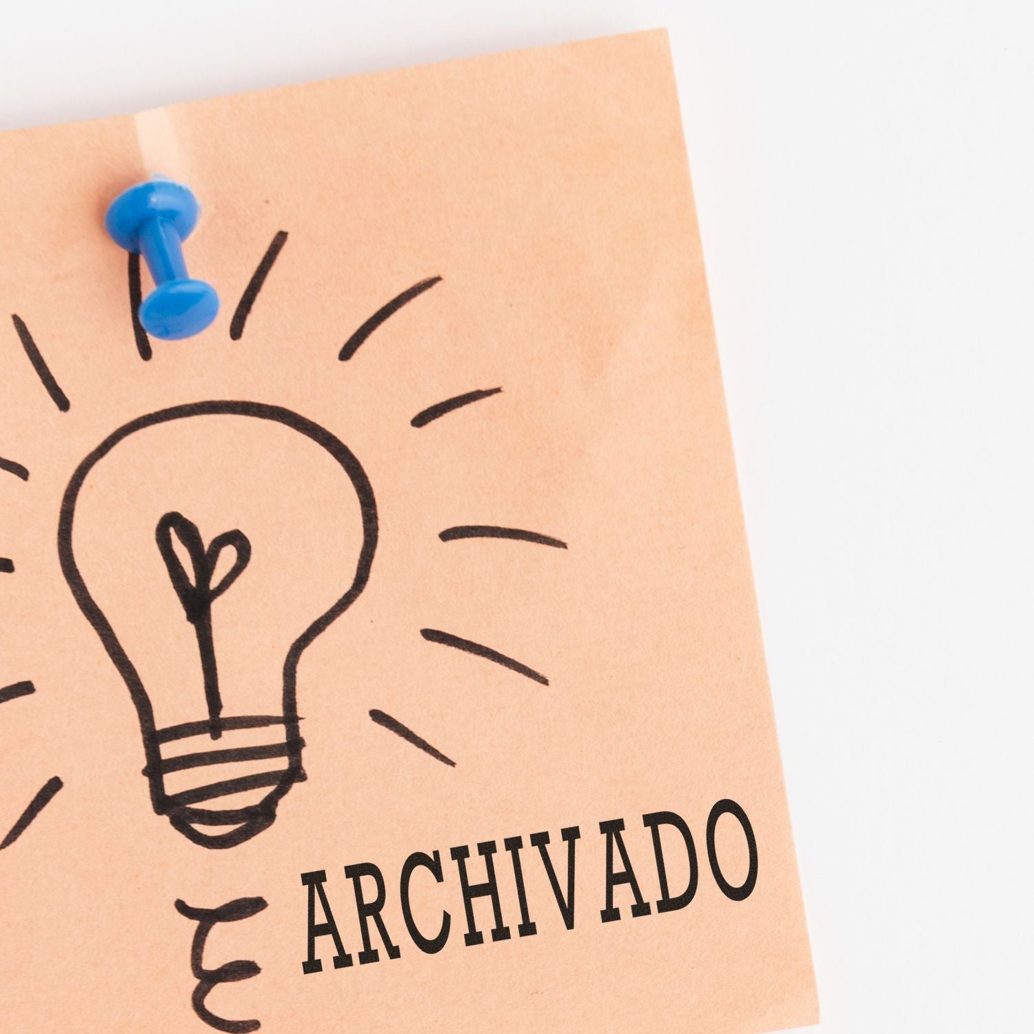 A sticky note with a lightbulb drawing and the word ARCHIVADO stamped using the Large Pre-Inked Archivado Stamp, pinned with a blue pushpin.