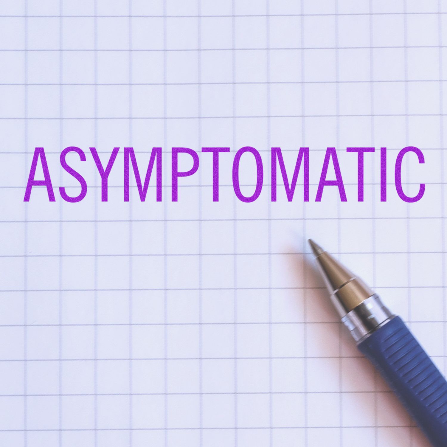 Asymptomatic rubber stamp impression in purple ink on graph paper with a blue pen beside it.