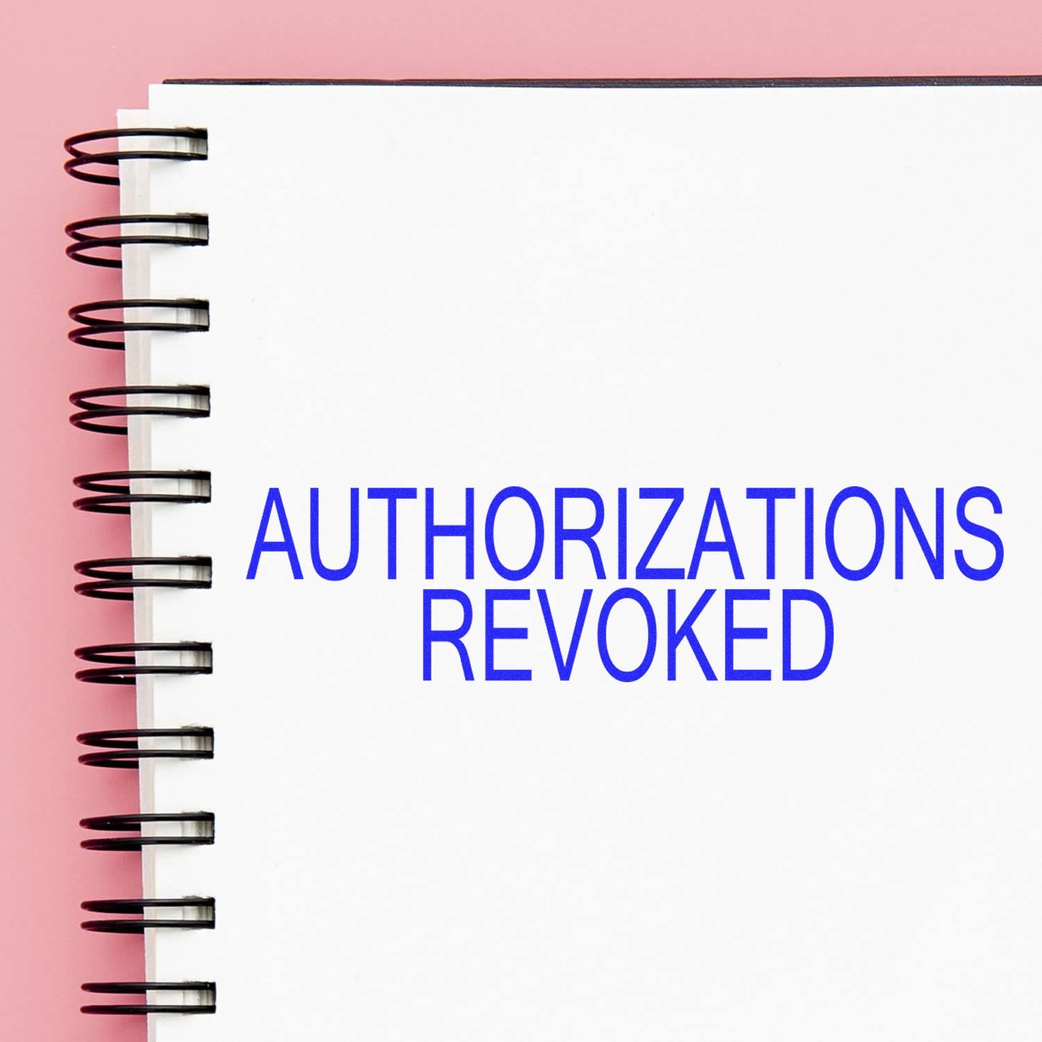 Large Self Inking Authorizations Revoked Stamp used on a white spiral notebook with a pink background.