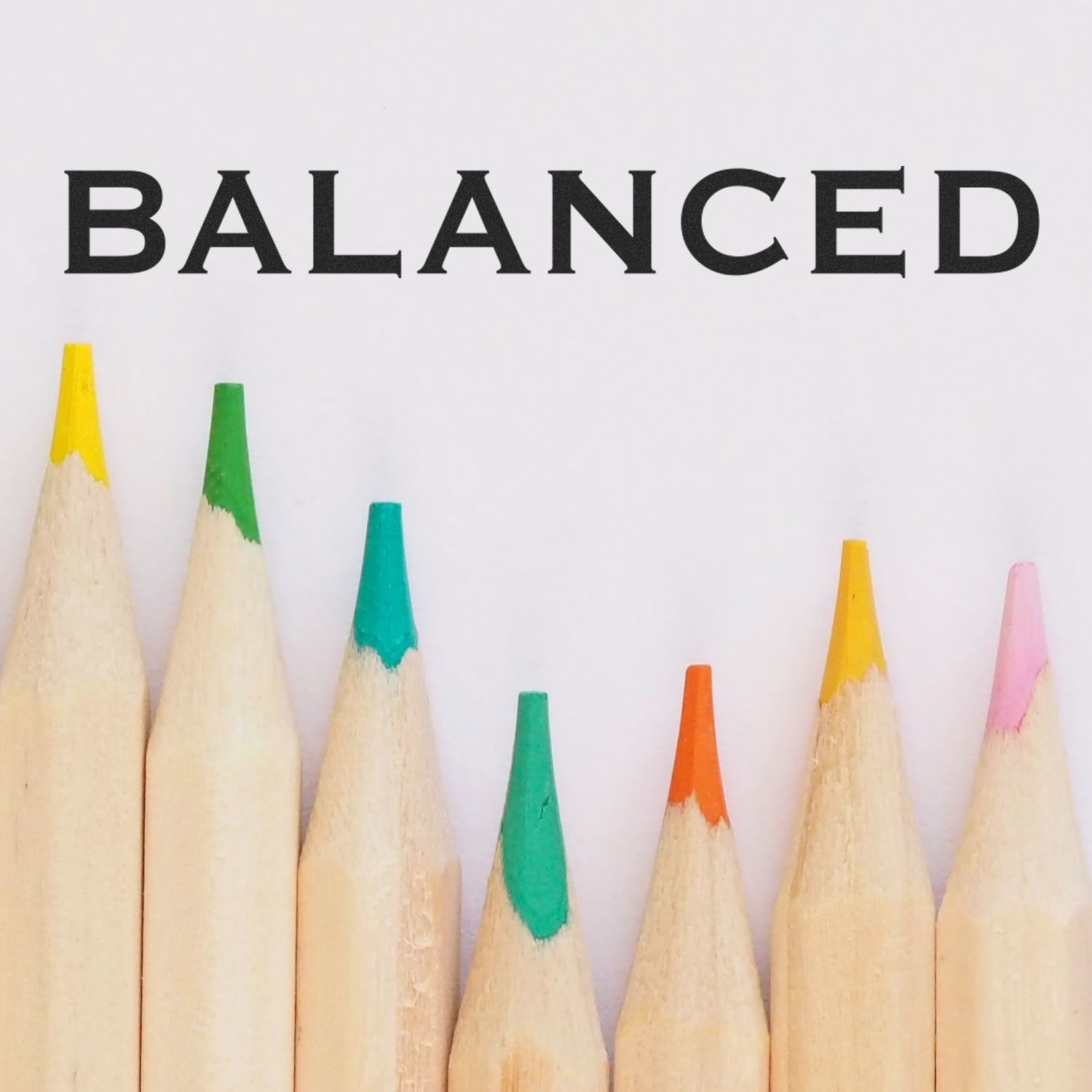 Colored pencils arranged in a row with the word BALANCED stamped above them, showcasing the Balanced Rubber Stamp.