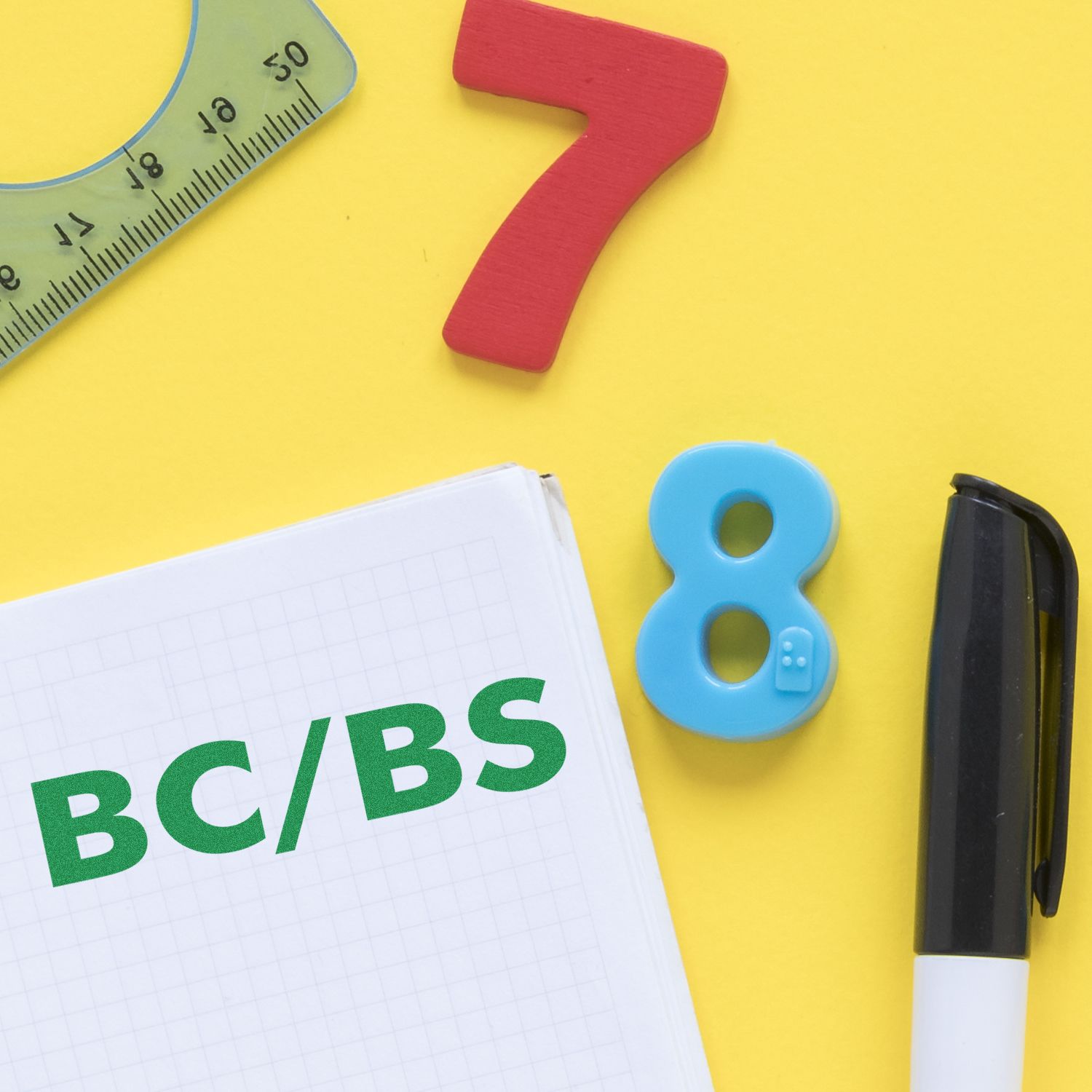 BC/BS Medical Provider Rubber Stamp on a notebook with a pen, ruler, and colorful numbers on a yellow background.