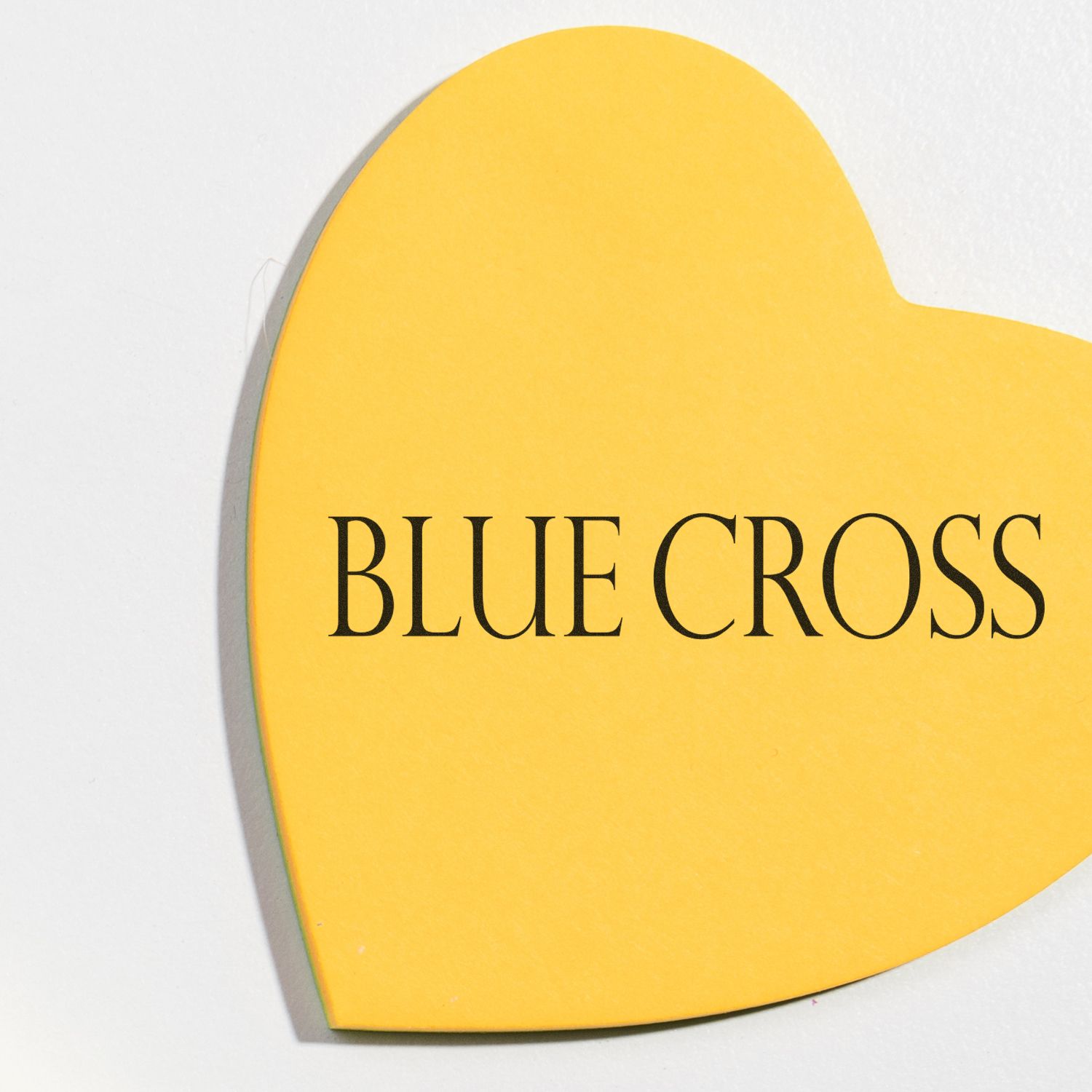 Yellow heart-shaped paper stamped with BLUE CROSS using the Large Pre-Inked Blue Cross Stamp.