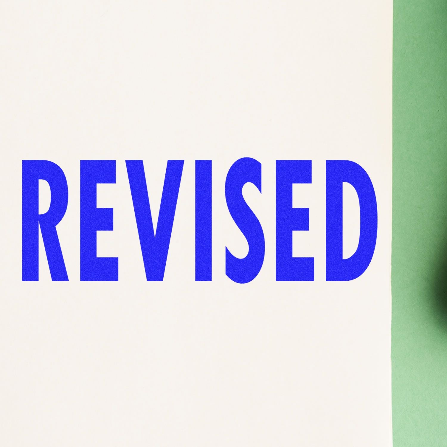 Self Inking Bold Revised Stamp imprint in blue ink on white paper with a green background, showing the word 'REVISED' in large, bold letters.