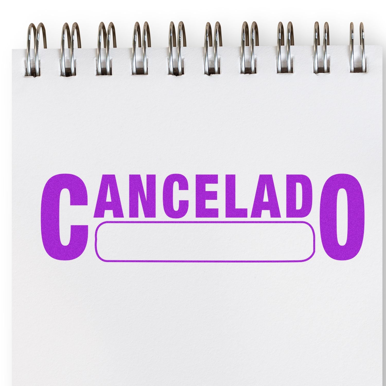 Cancelado with Box Rubber Stamp in use on a spiral notebook, displaying the word 'Cancelado' in bold purple letters with a blank box.