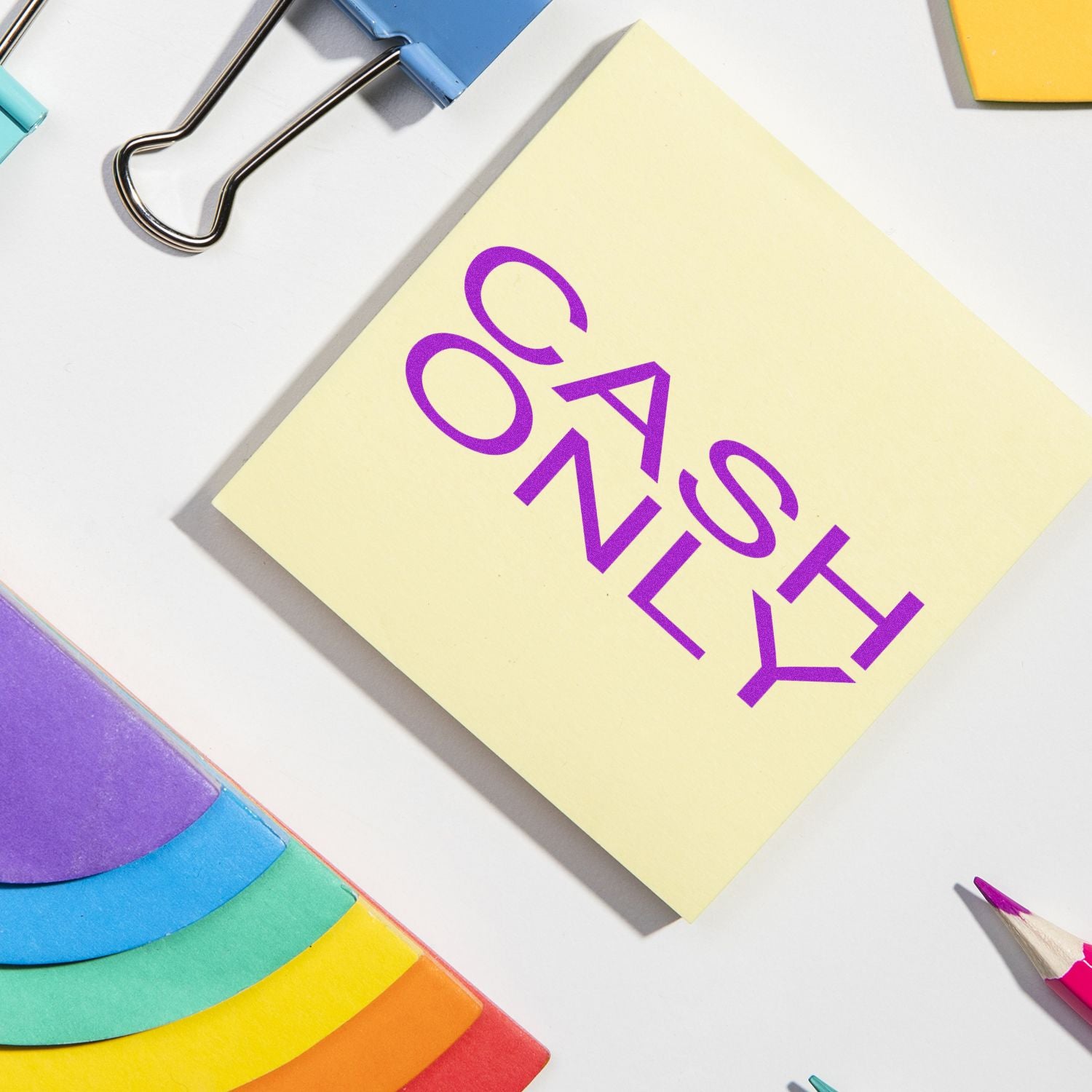 Large Cash Only Rubber Stamp imprint on a yellow sticky note, surrounded by colorful office supplies on a white desk.