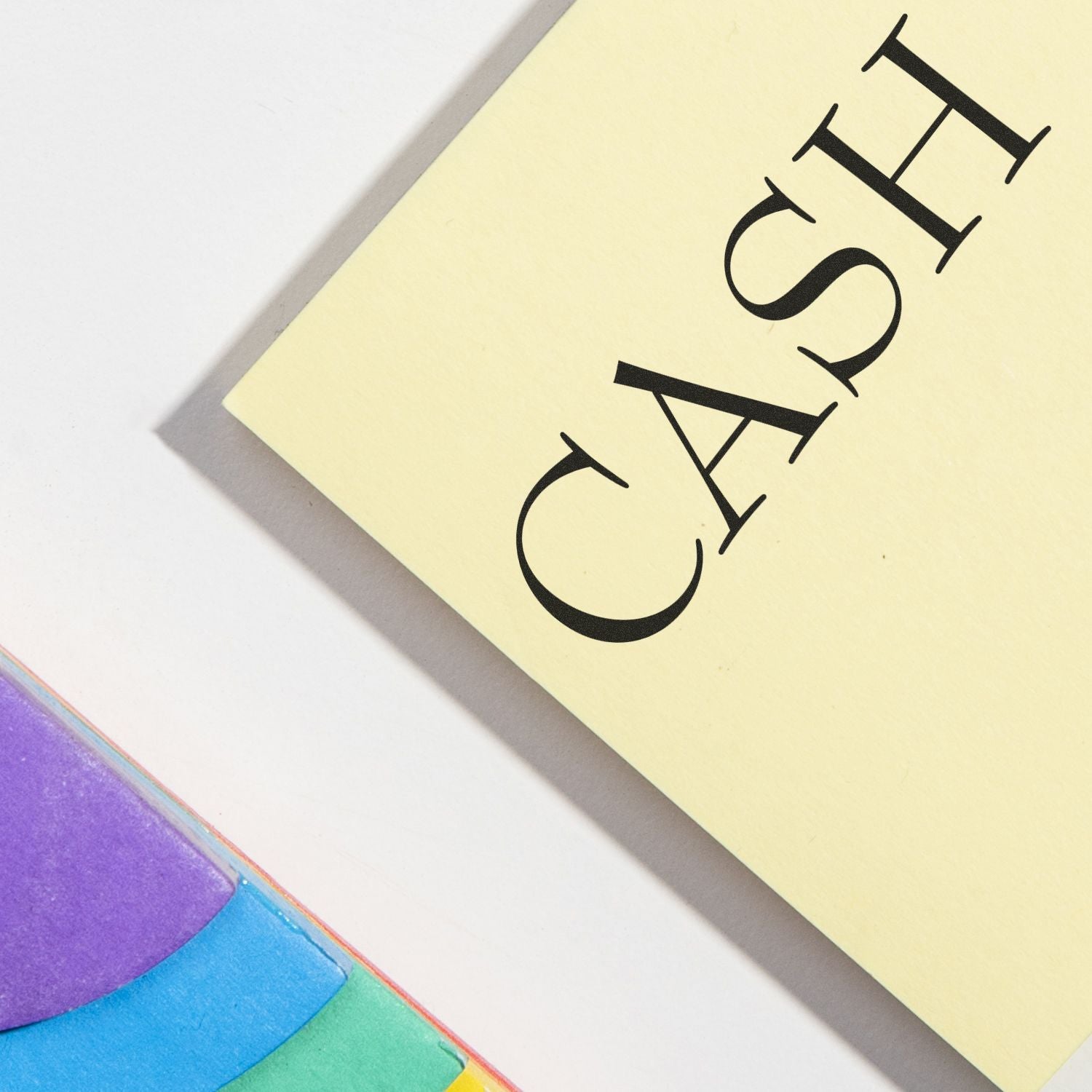 Yellow paper stamped with 'CASH' in bold black letters, next to colorful sticky notes, highlighting a cash rubber stamp in use.