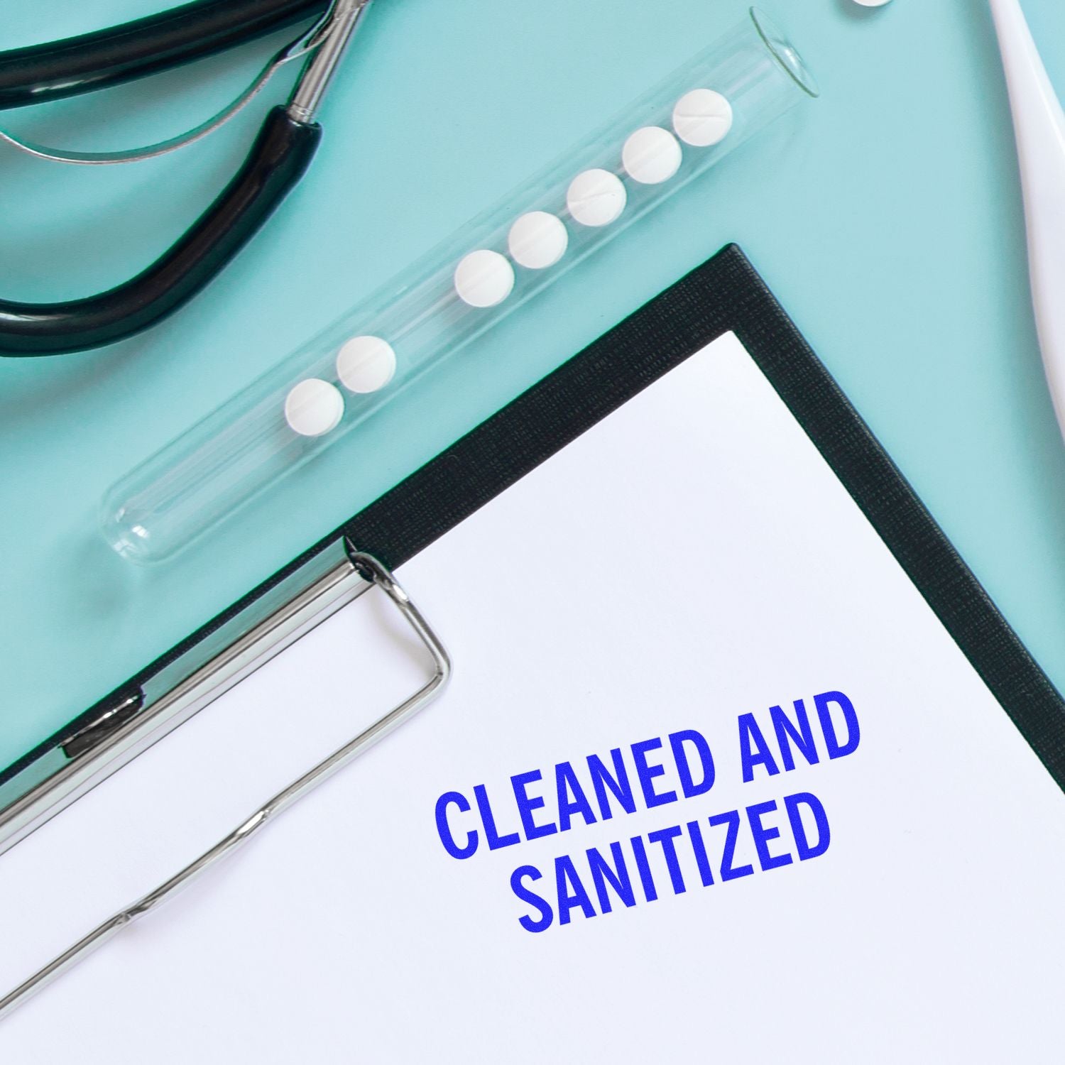 A clipboard with a Cleaned and Sanitized rubber stamp, next to a stethoscope and a test tube with tablets on a light blue surface.