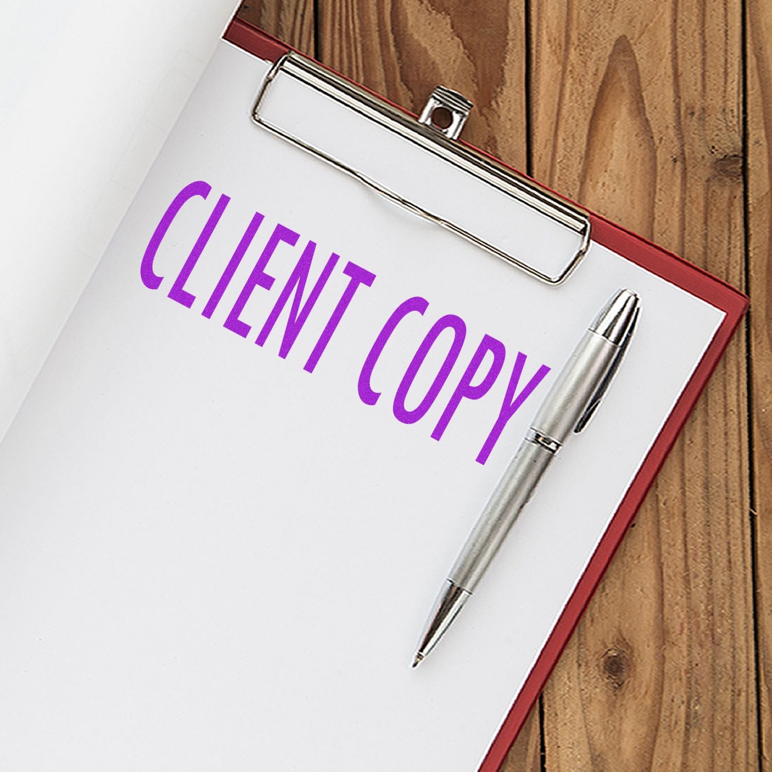 A clipboard with a document stamped CLIENT COPY in purple ink using the Large Client Copy Rubber Stamp, next to a silver pen.