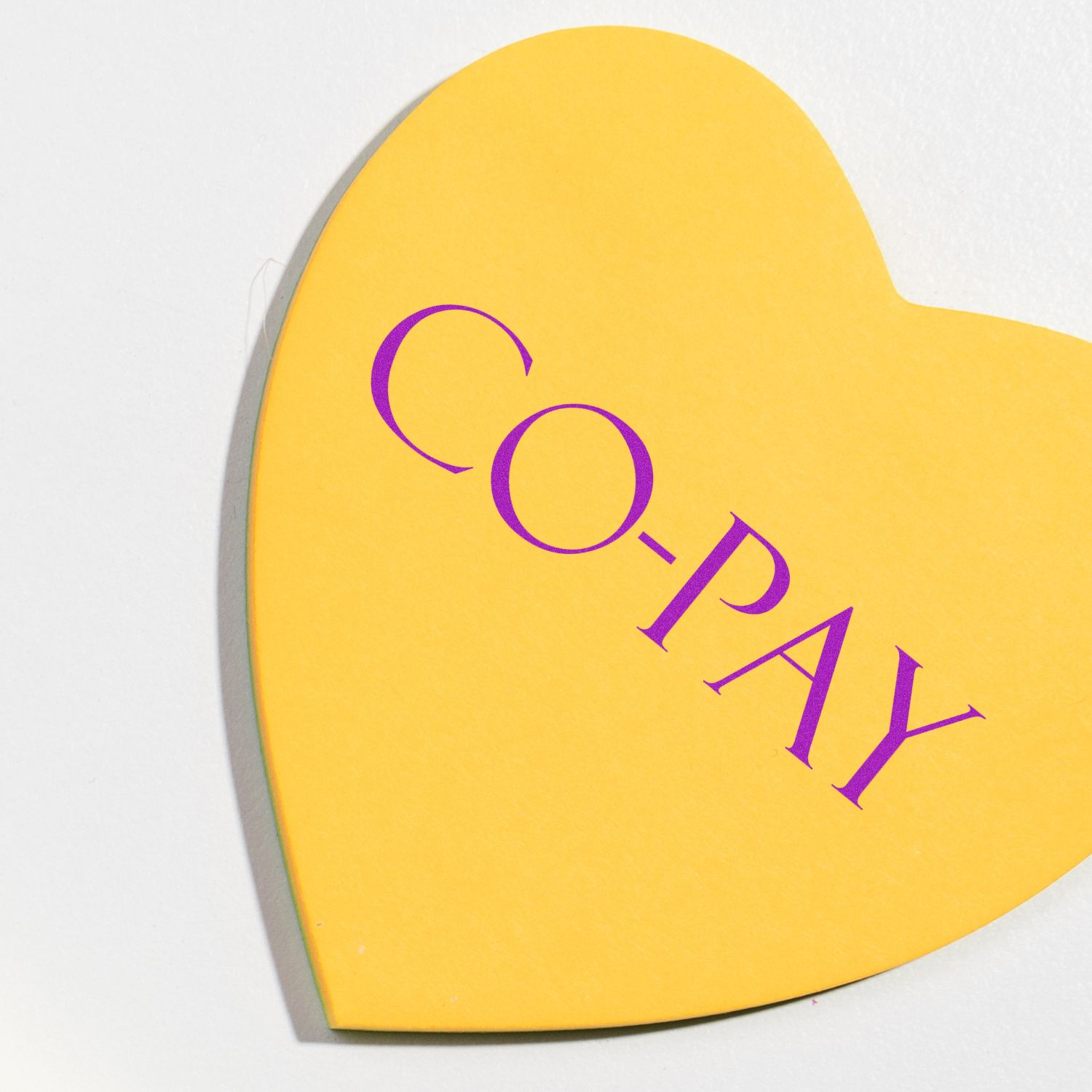 Yellow heart-shaped Medical Co-Pay rubber stamp with purple text CO-PAY on a white background.