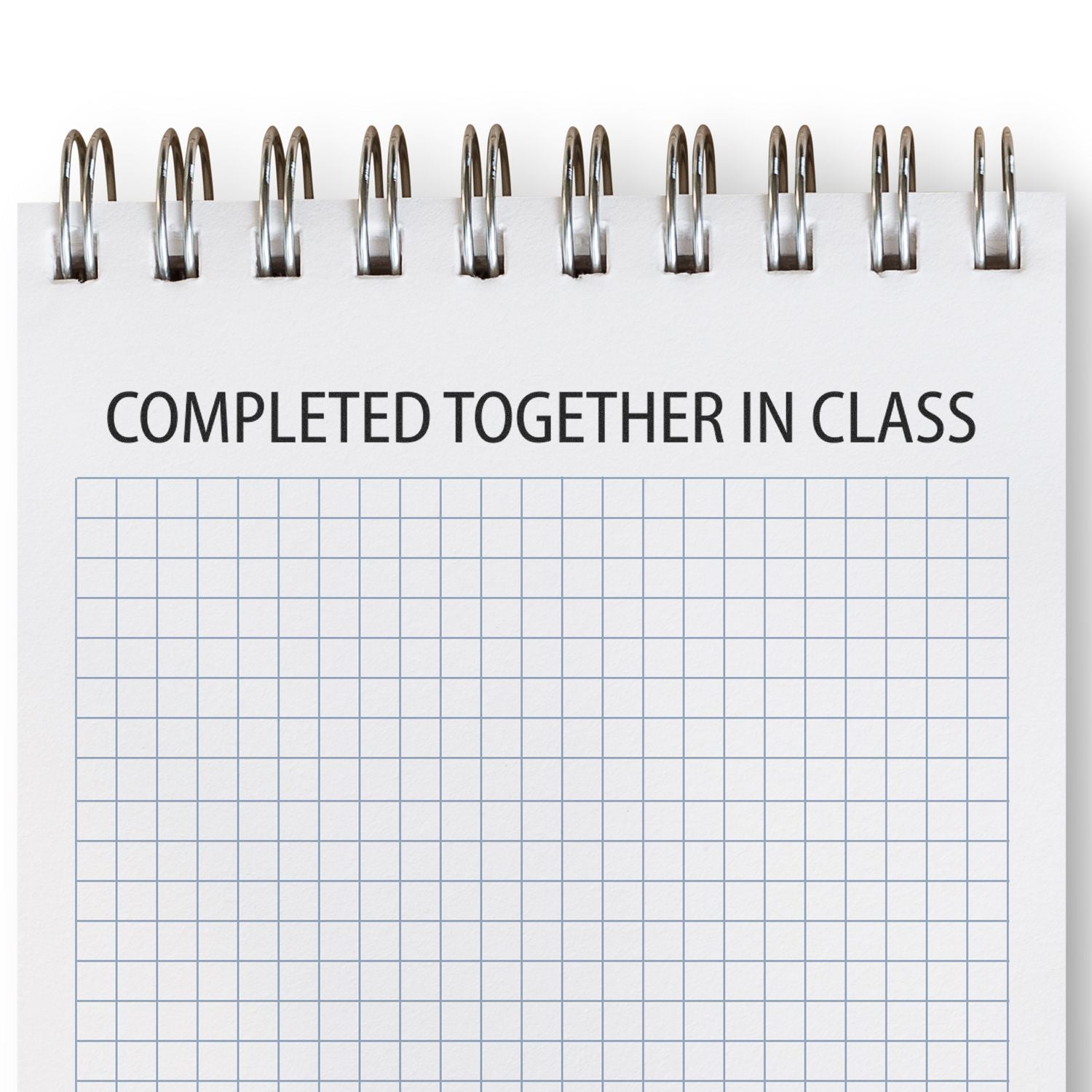 A notebook with a grid pattern and the text COMPLETED TOGETHER IN CLASS stamped on it using the Completed Together In Class Rubber Stamp.