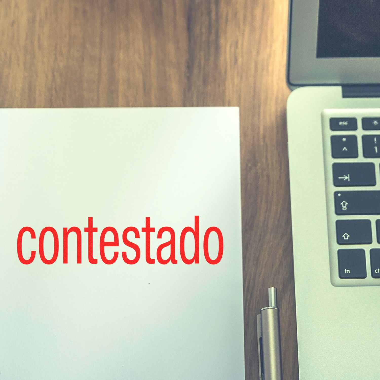 Contestado Rubber Stamp in use on white paper beside a laptop and pen on a wooden desk.