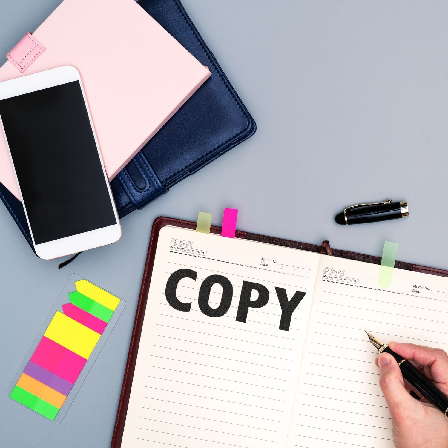 Person using Large Copy Rubber Stamp on a notebook, surrounded by colorful sticky notes, a smartphone, and a pen on a desk.