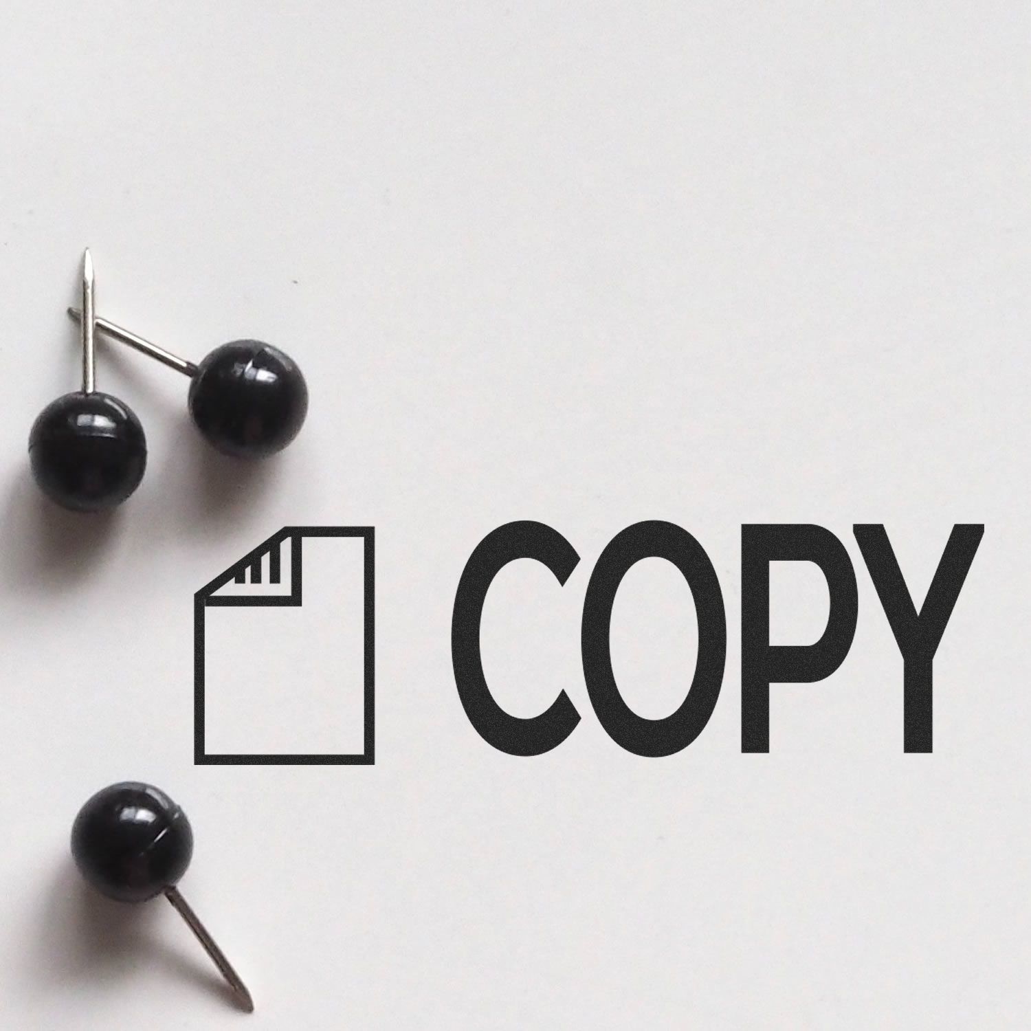 "Copy with Letter Rubber Stamp" imprint on white paper with two black push pins nearby.