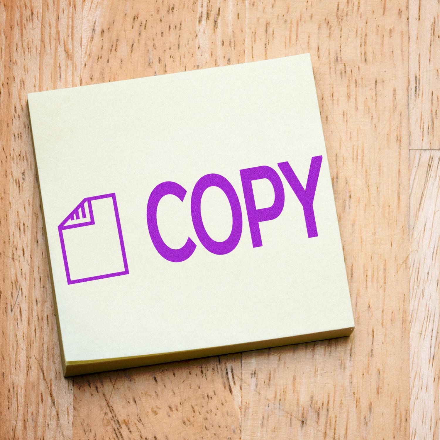 Copy with Letter Rubber Stamp imprint on a yellow sticky note, placed on a wooden surface.