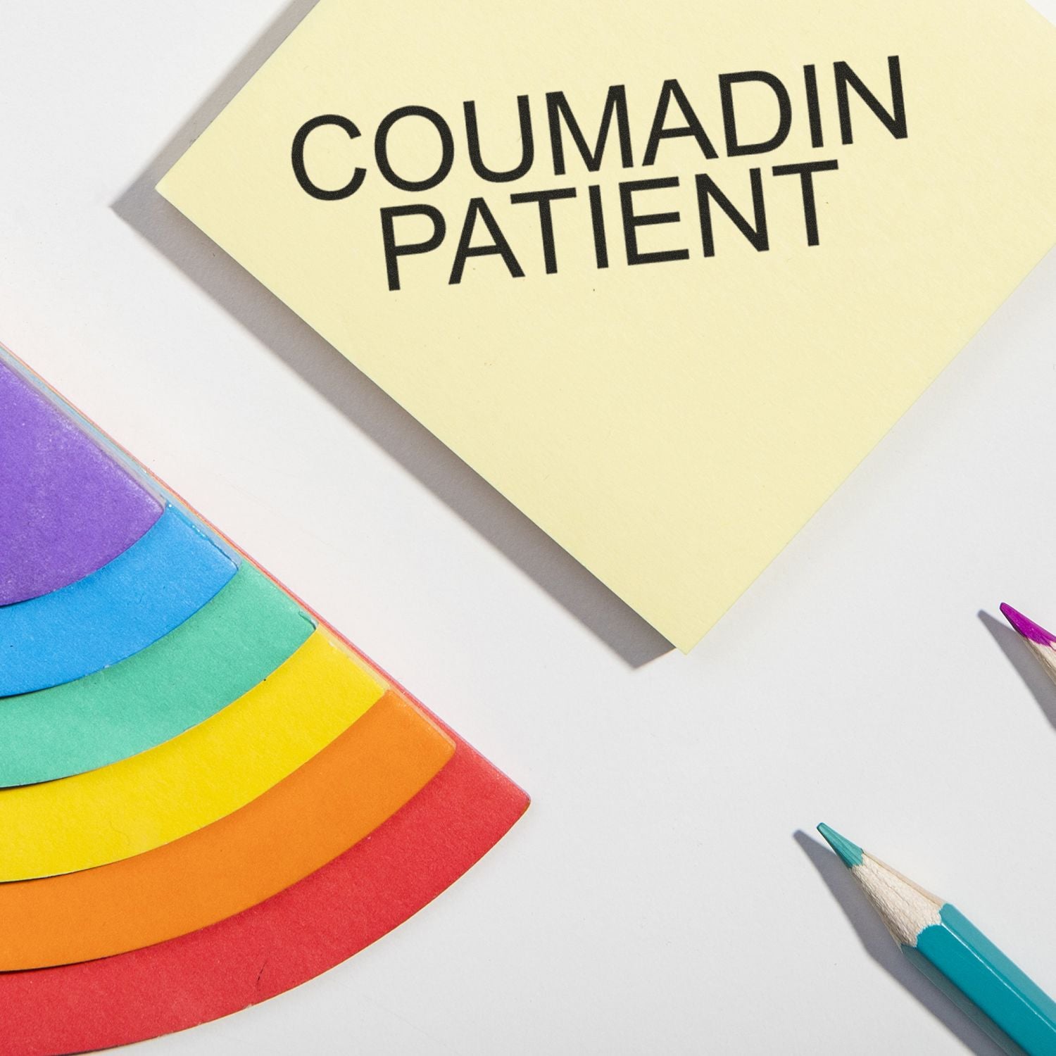 Large Coumadin Patient Rubber Stamp used on a yellow sticky note, surrounded by colorful paper and pencils on a white surface.