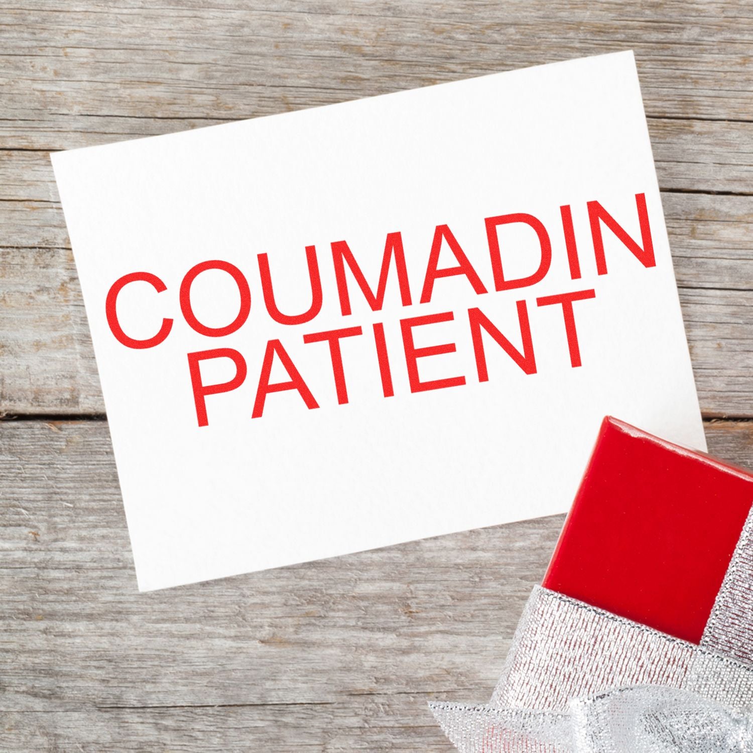 Coumadin Patient Rubber Stamp in use, displaying bold red text COUMADIN PATIENT on a white card, placed on a wooden surface.