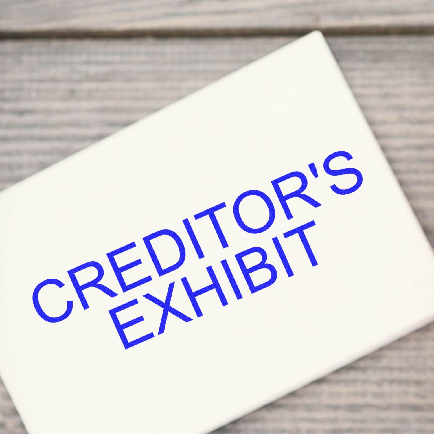 Creditors Exhibit Rubber Stamp in blue ink on a white surface, placed on a wooden background.