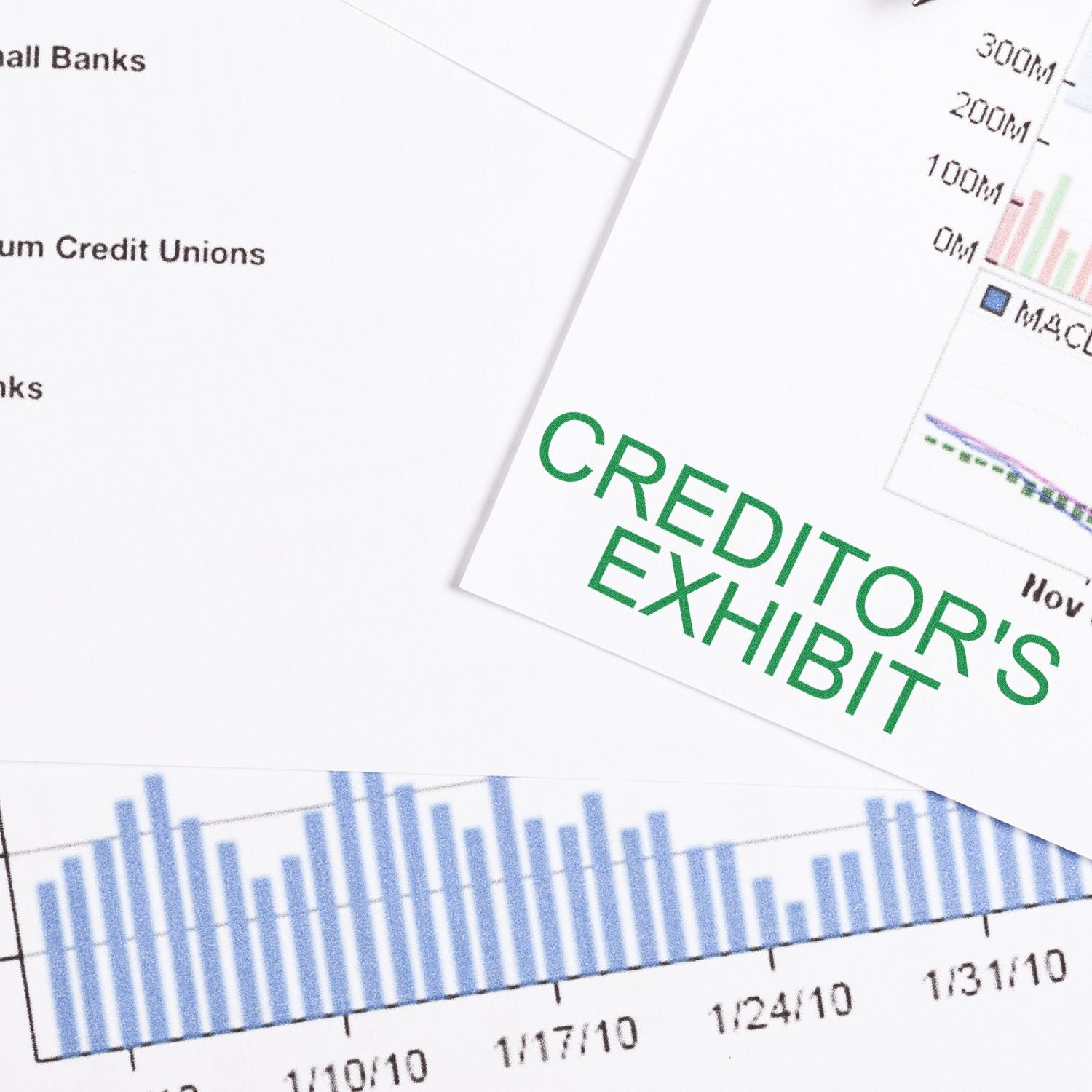 Large Self Inking Creditors Exhibit Stamp in green ink on a document with financial graphs and charts in the background.